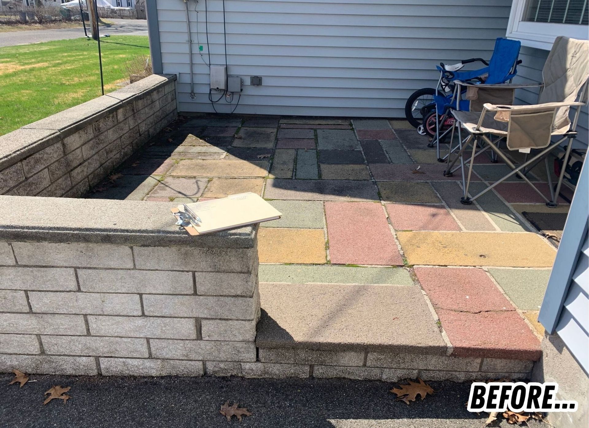 Small paved patio with a low brick wall, chairs, and a house exterior, labeled BEFORE.”