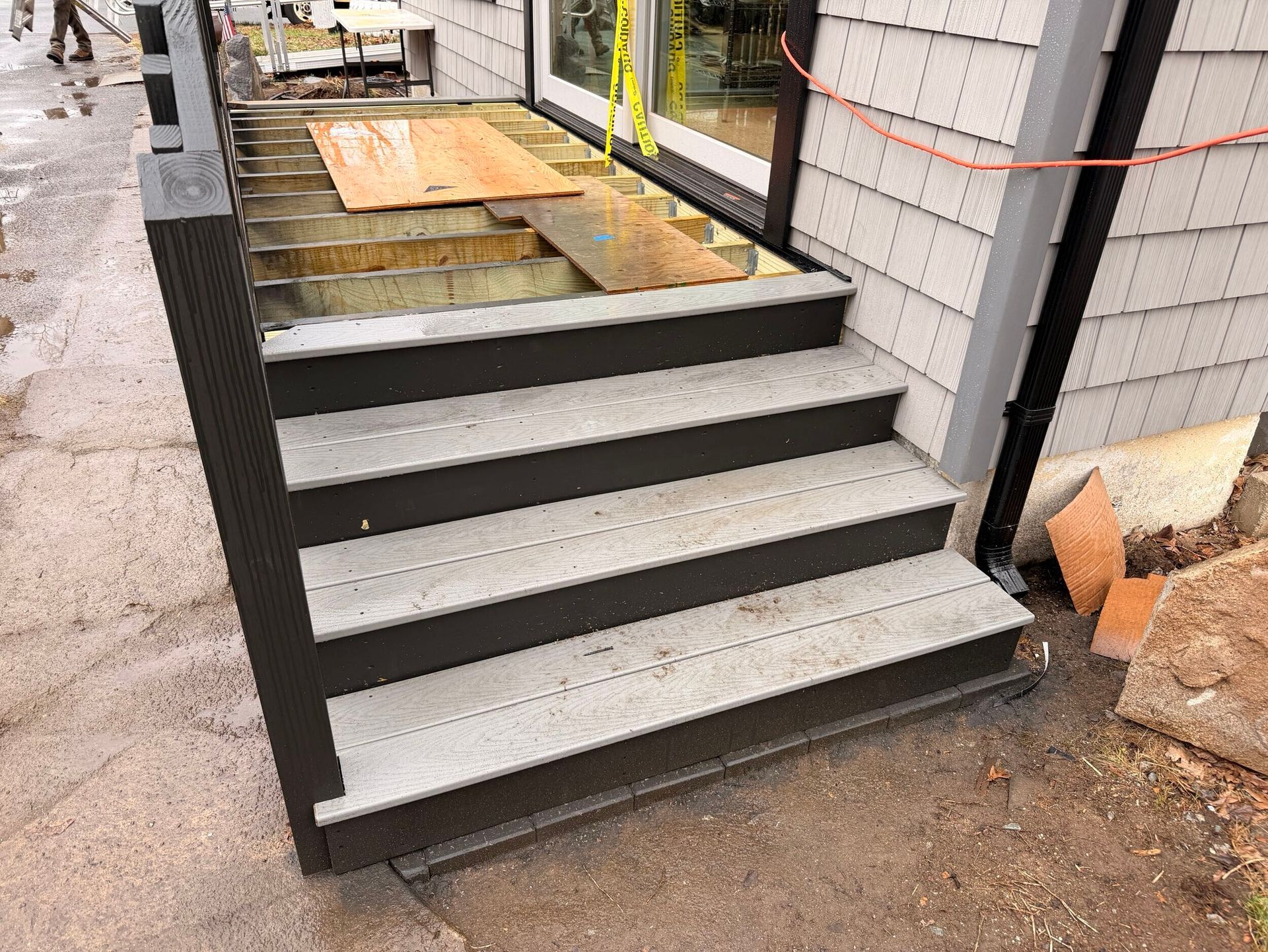 House steps under construction with dark trim, unfinished porch, and wooden boards on the landing
