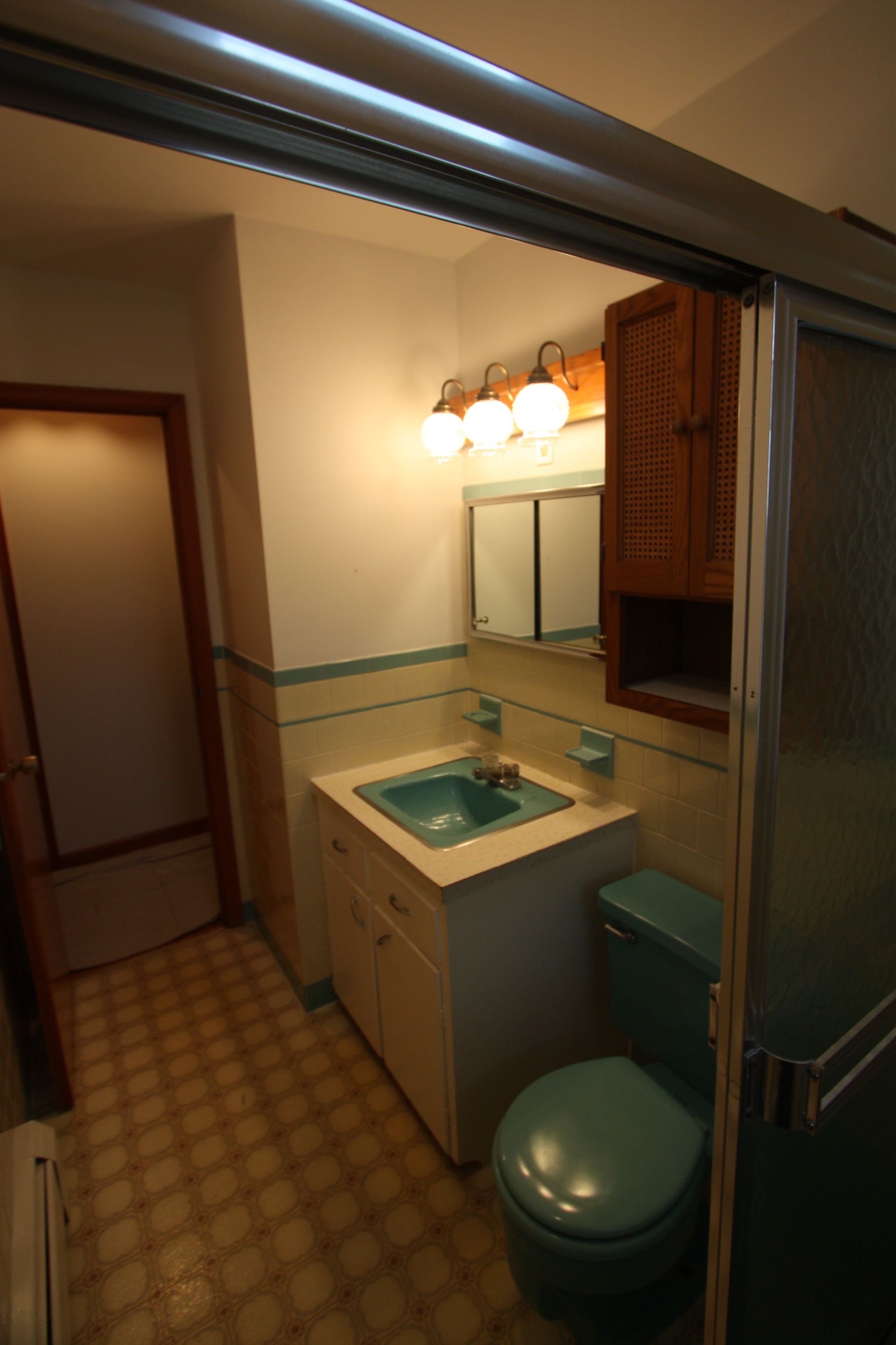 A bathroom with a toilet, a sink, and a mirror.