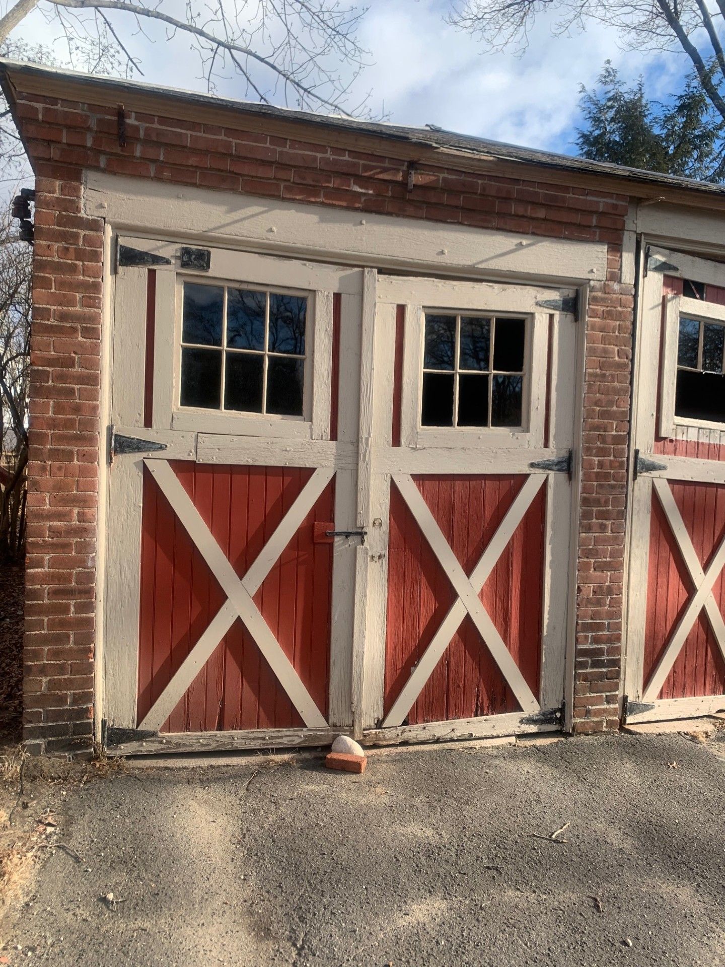 Red and white barn doors with windows in a brick building.