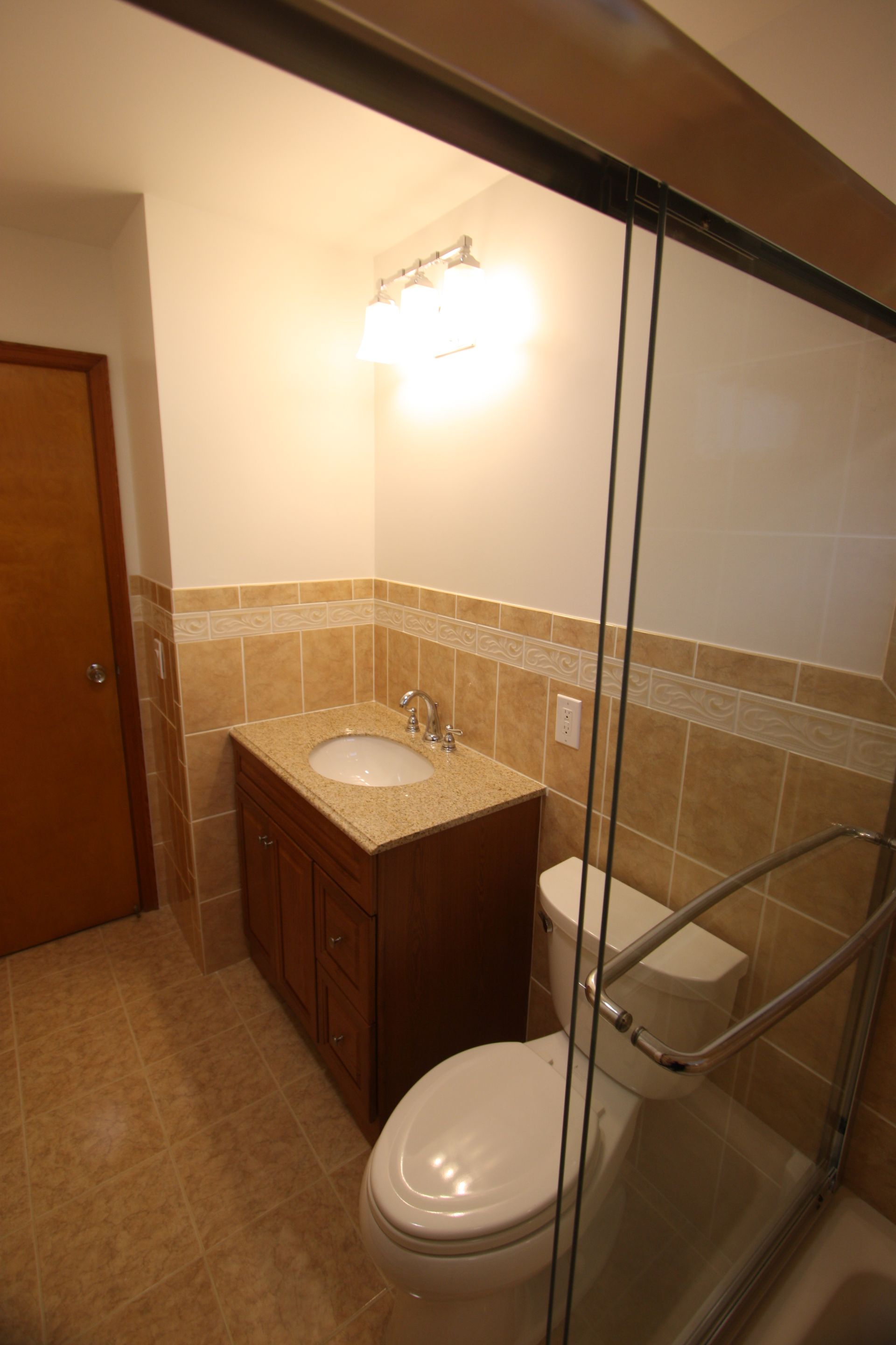 A bathroom with a toilet, a sink, and a sliding glass door.