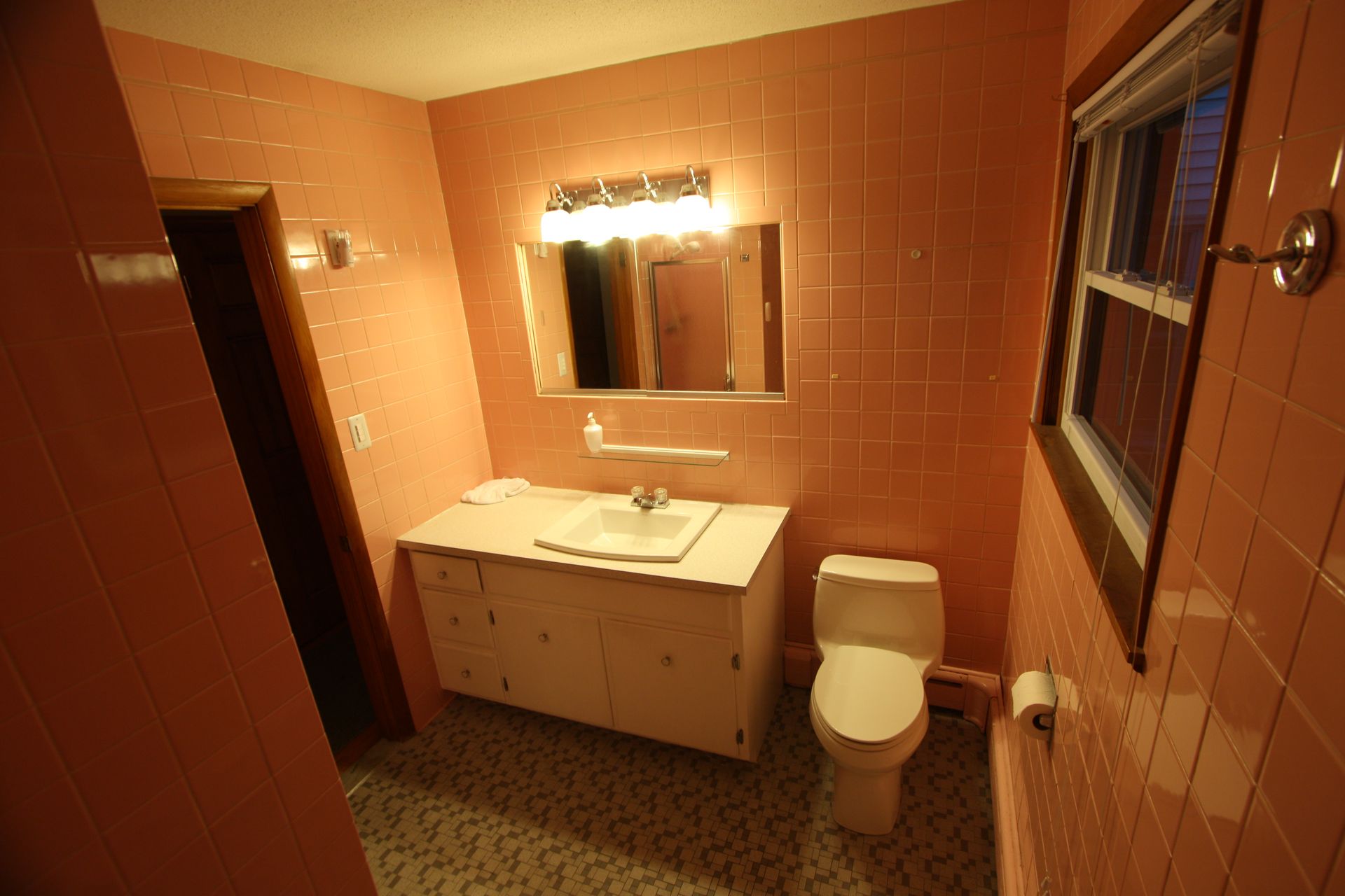 A bathroom with pink tiles, a toilet, and sink