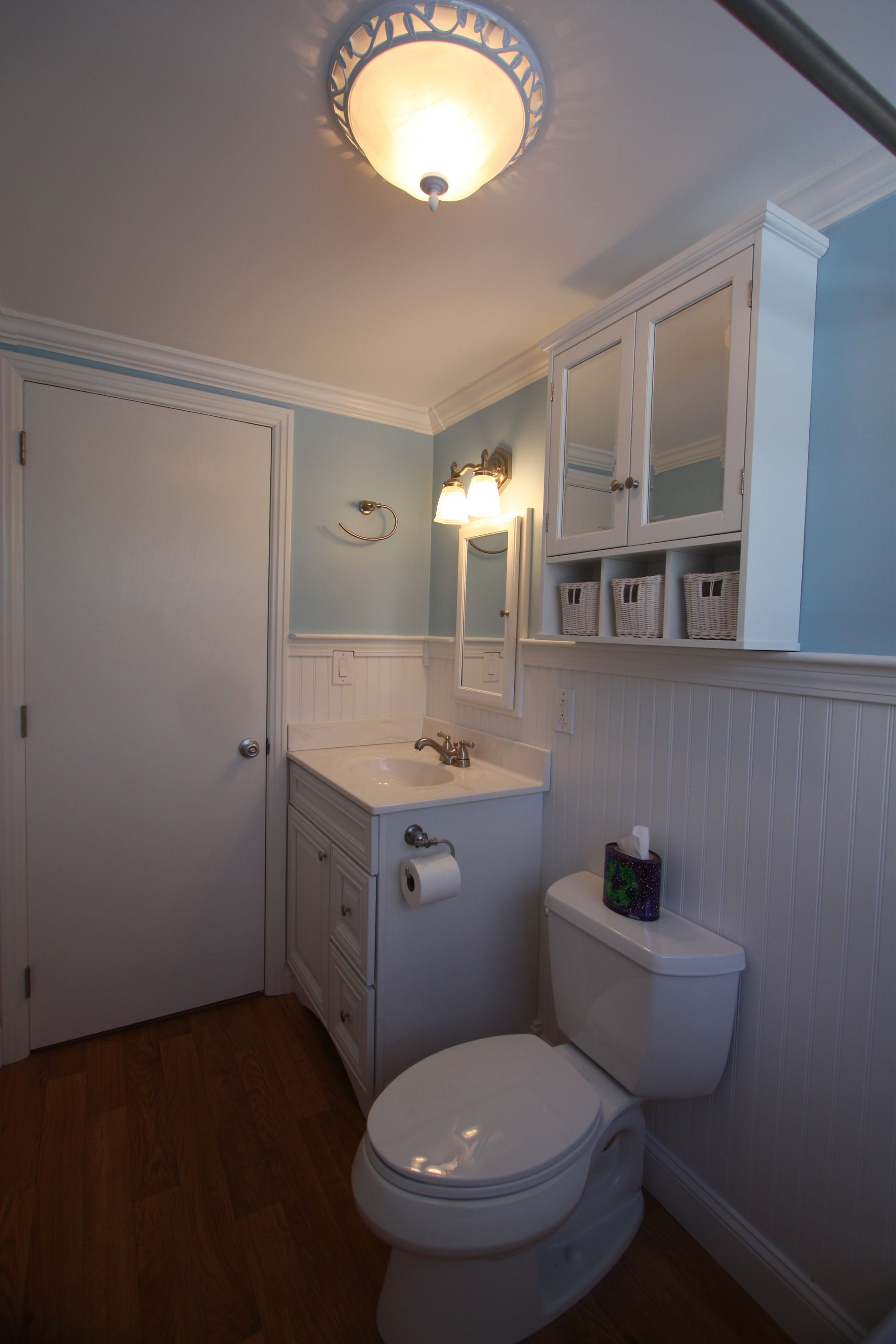 A bathroom with a toilet, sink, and mirror.