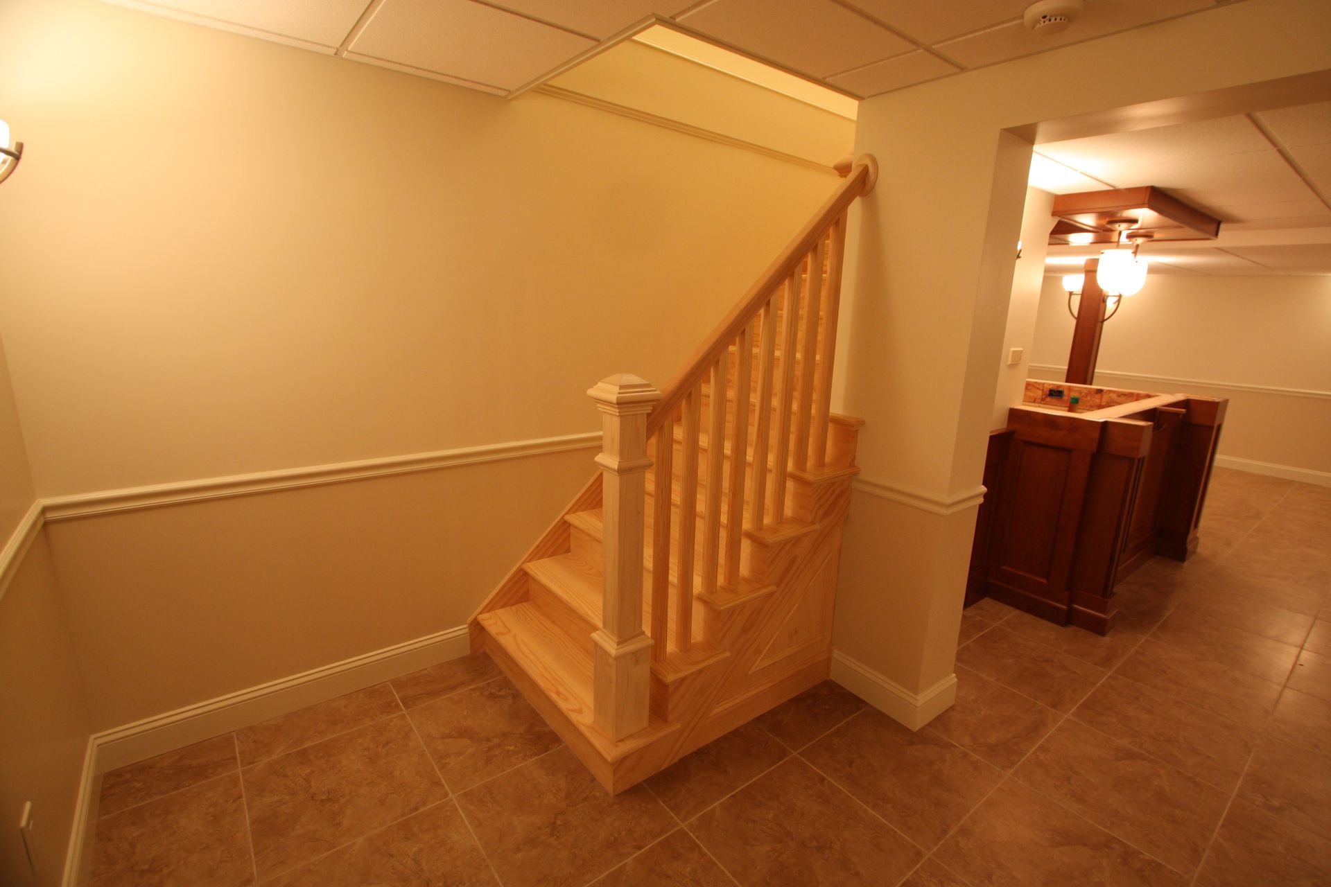 A staircase in a basement with a wooden railing.
