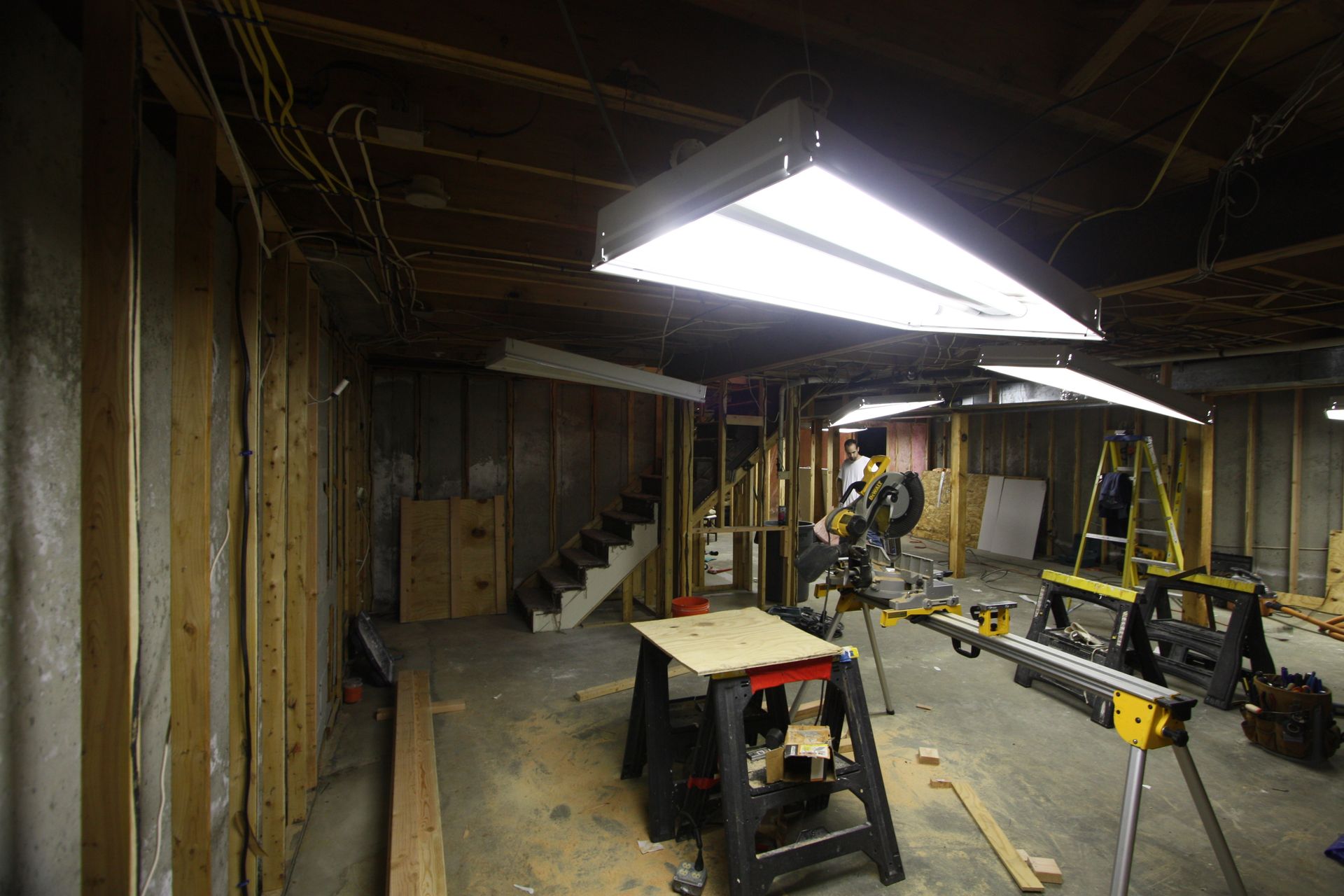 A man is cutting wood in a basement with a circular saw.