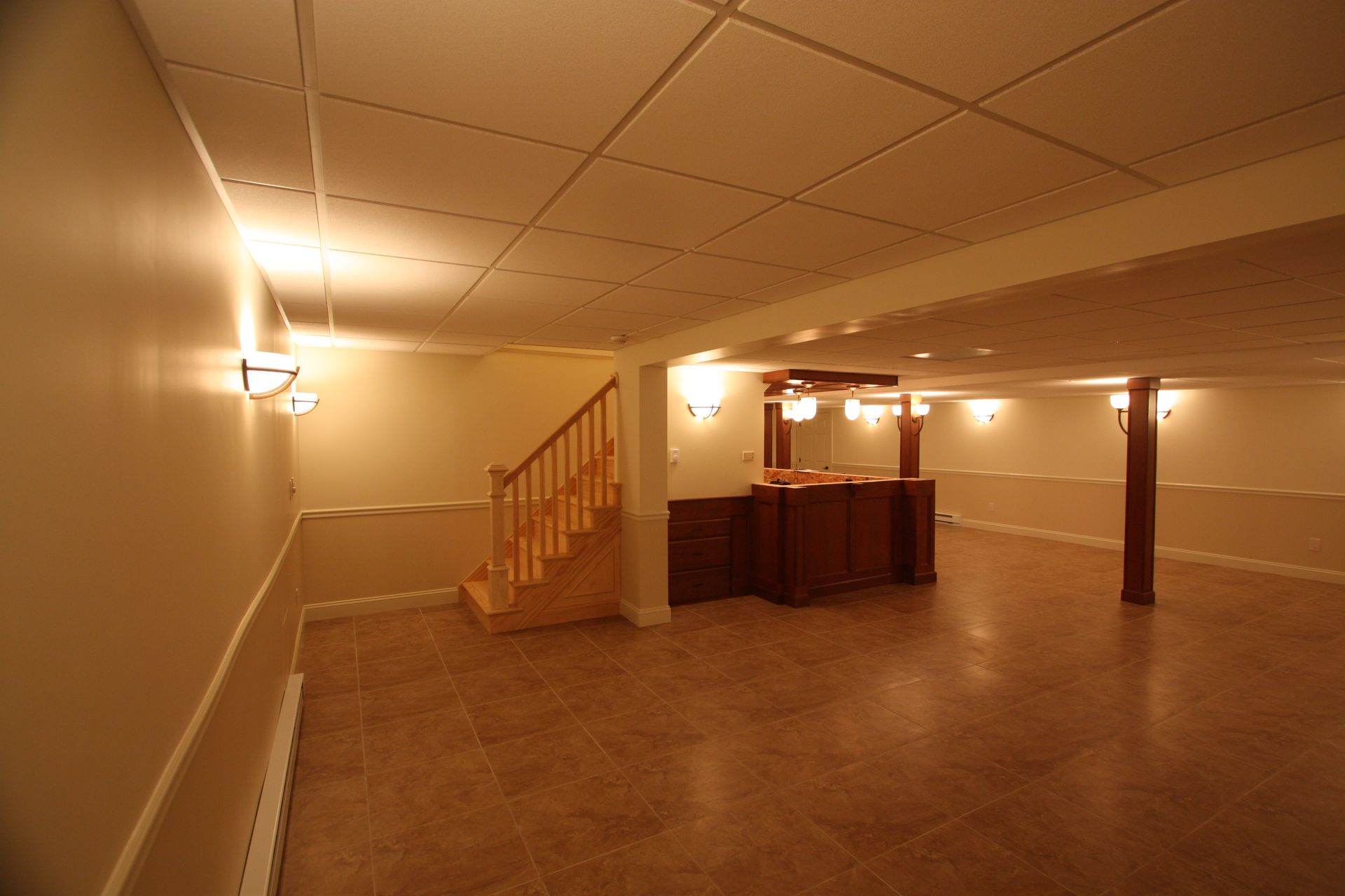 An empty basement with a bar and stairs.