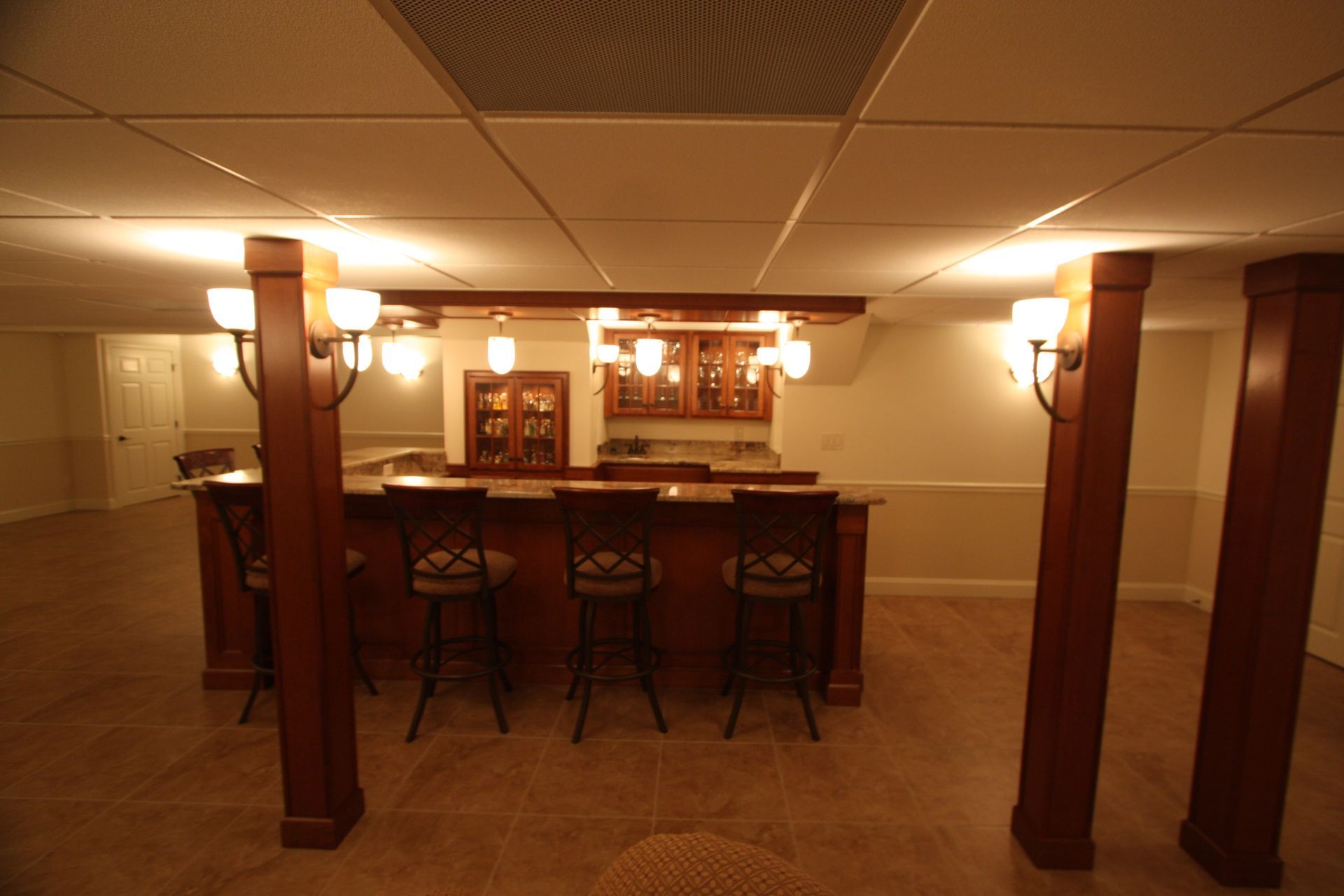 An empty basement with a bar and stools.