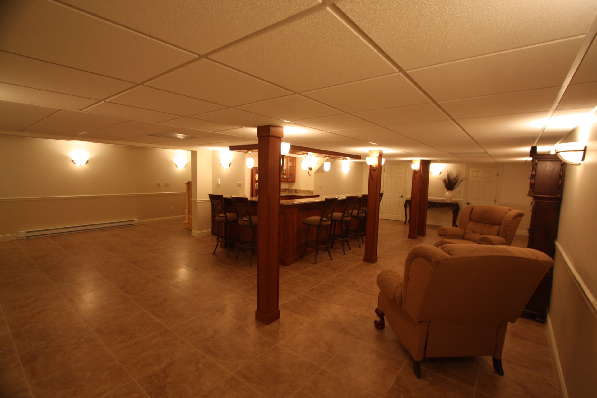 An empty basement with a bar and chairs.