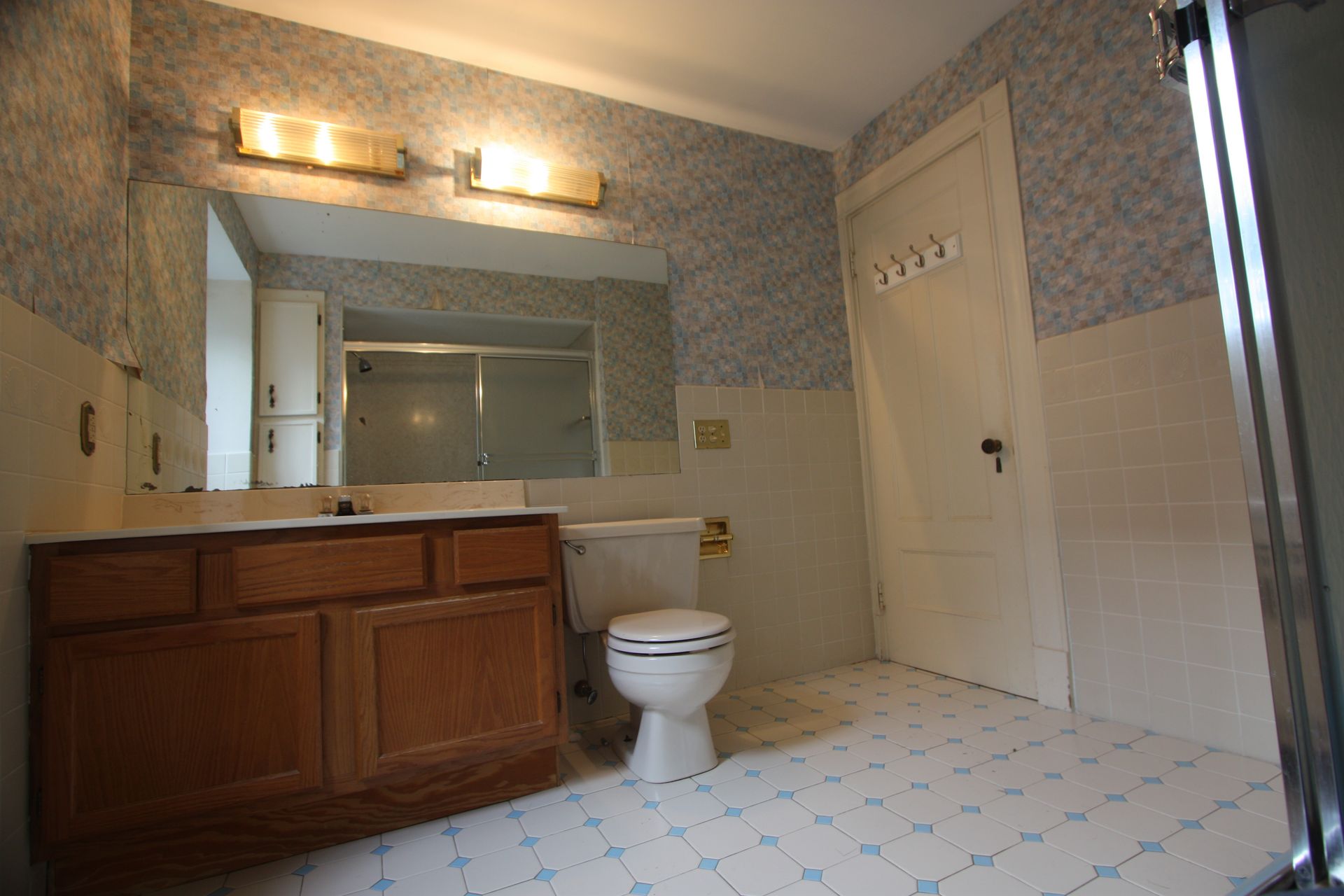 A bathroom with a toilet, sink, mirror, and shower.