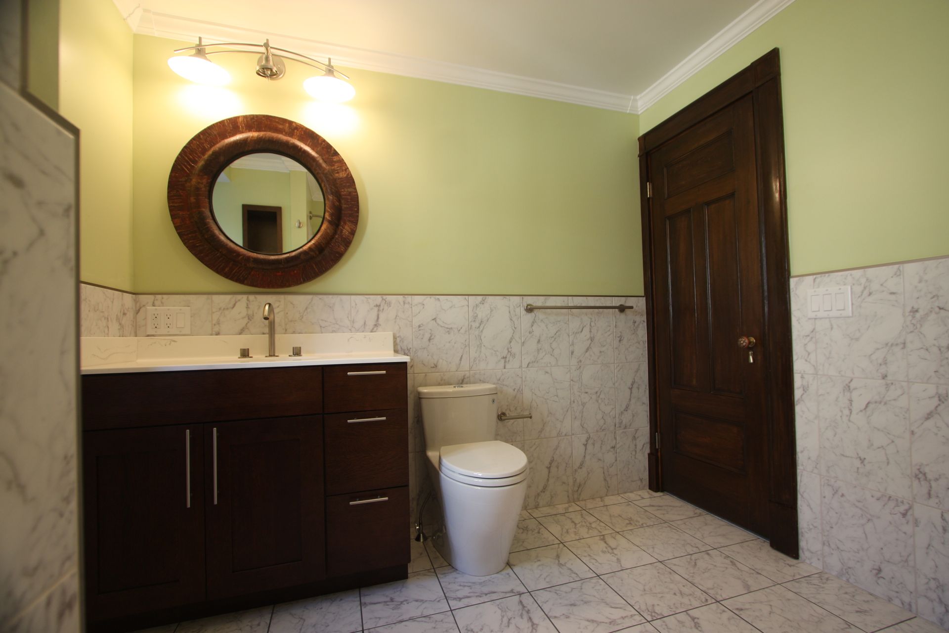 A bathroom with a toilet, a sink, and a mirror