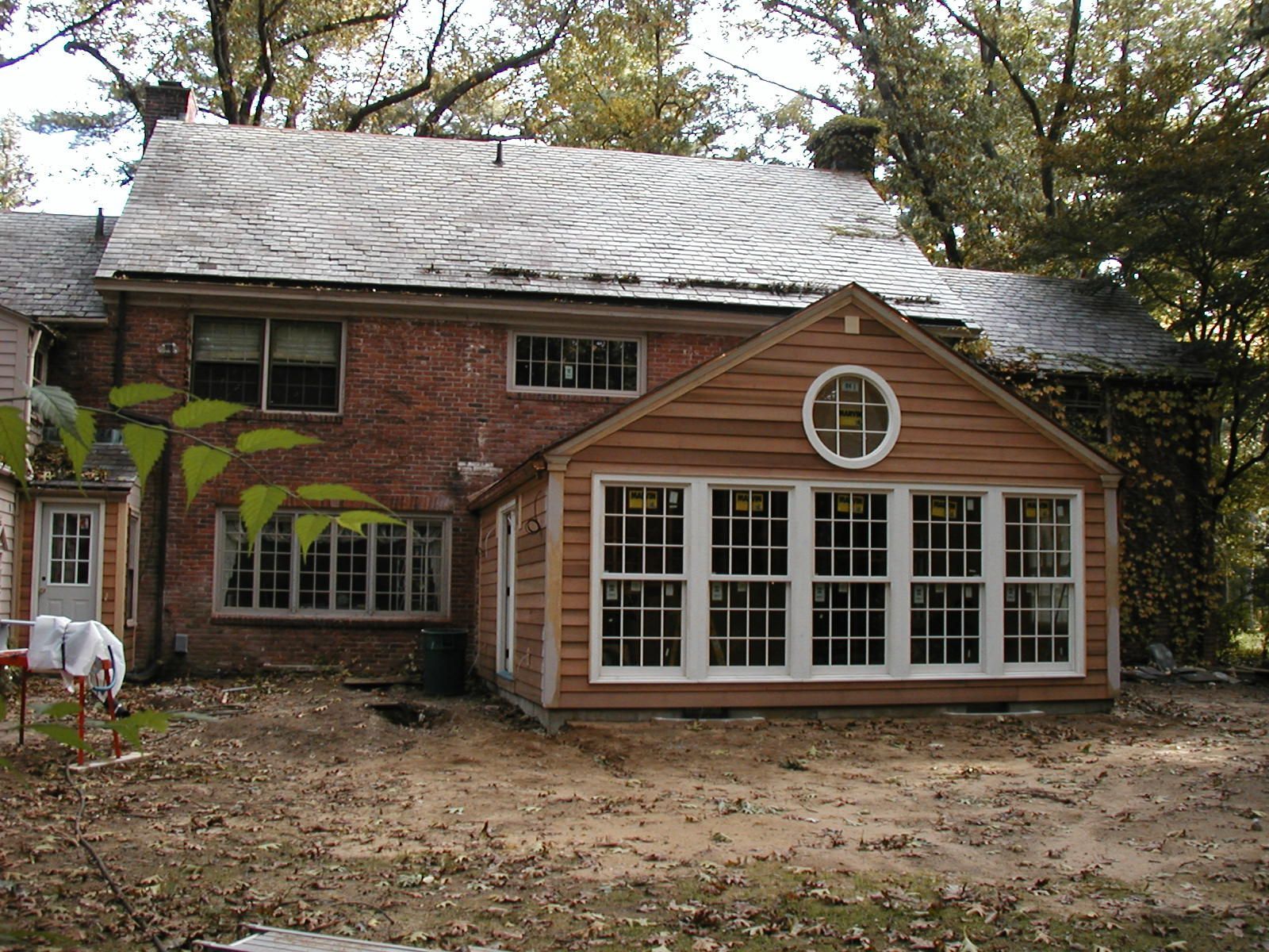 A brick house with a wooden sunroom attached to it.