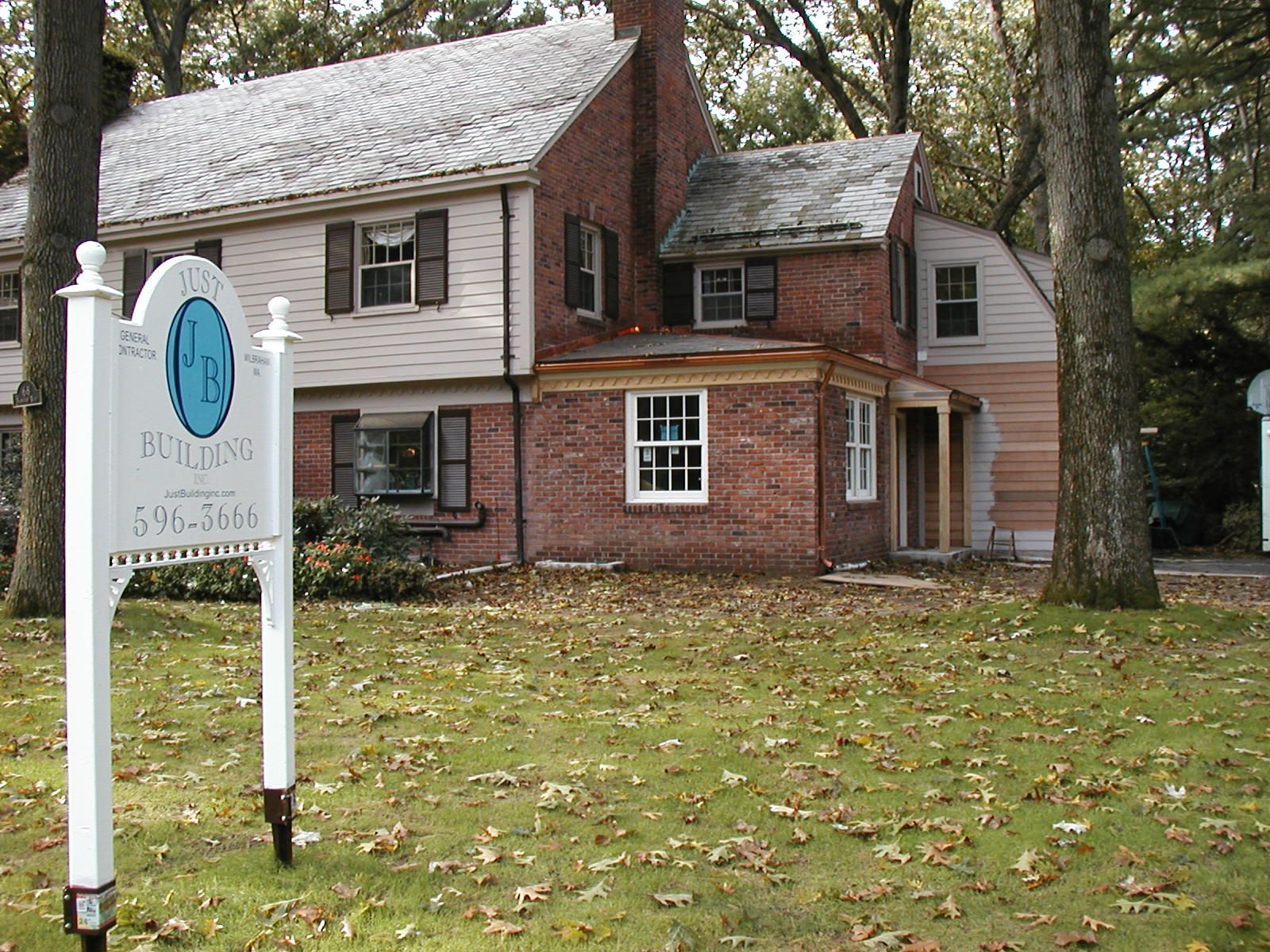 A brick house with a white sign in front of it.