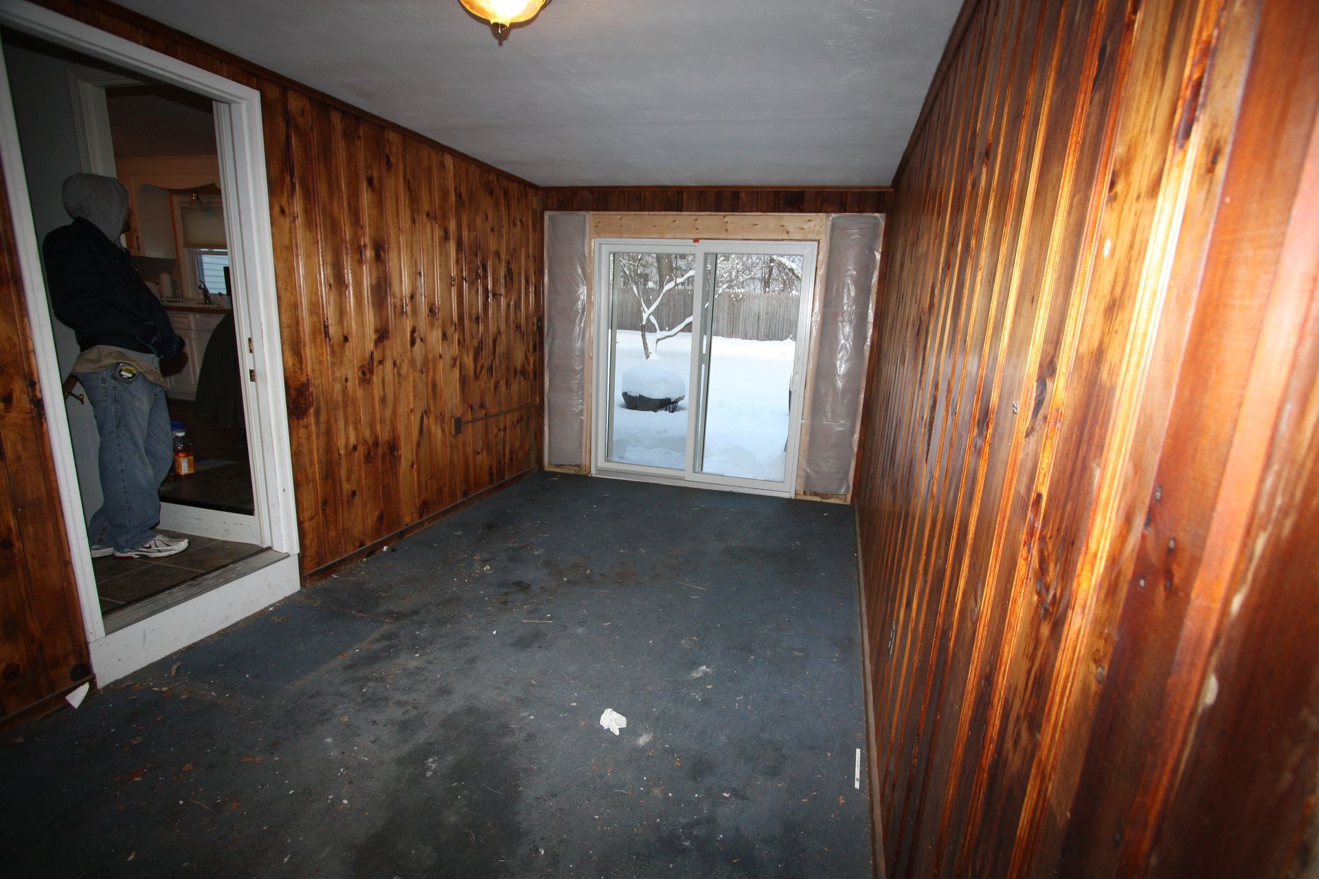 An empty room with wood paneling and a sliding glass door.