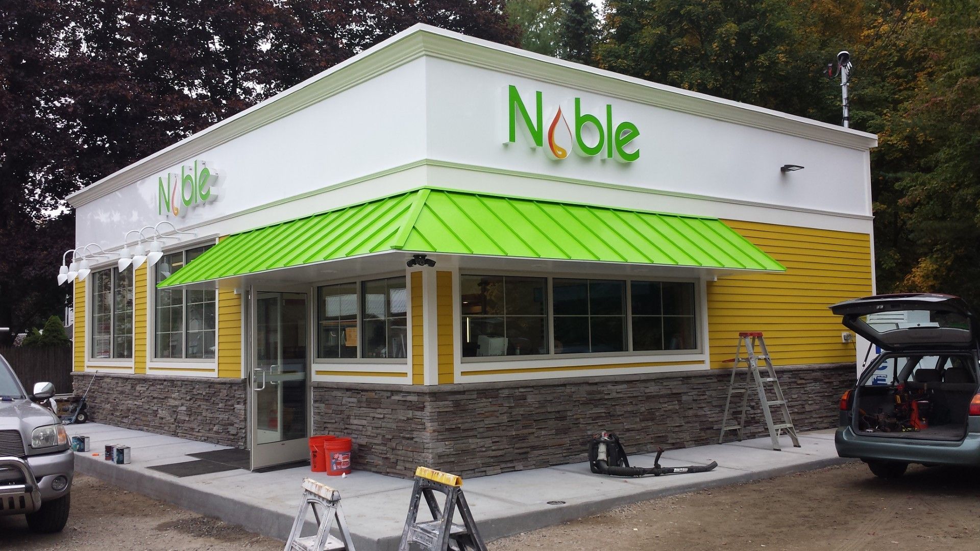 Noble restaurant with lime green awning, white and yellow walls, and a stone facade.