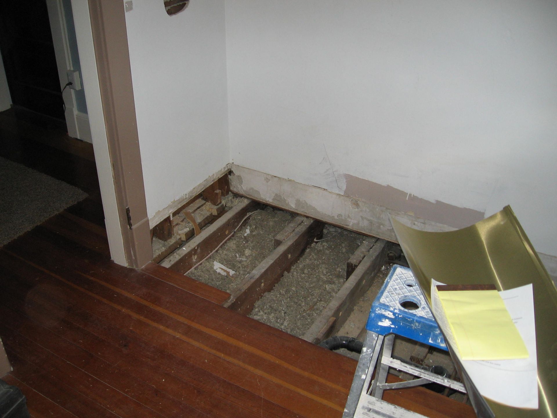 A room with a wooden floor and a ladder in it.