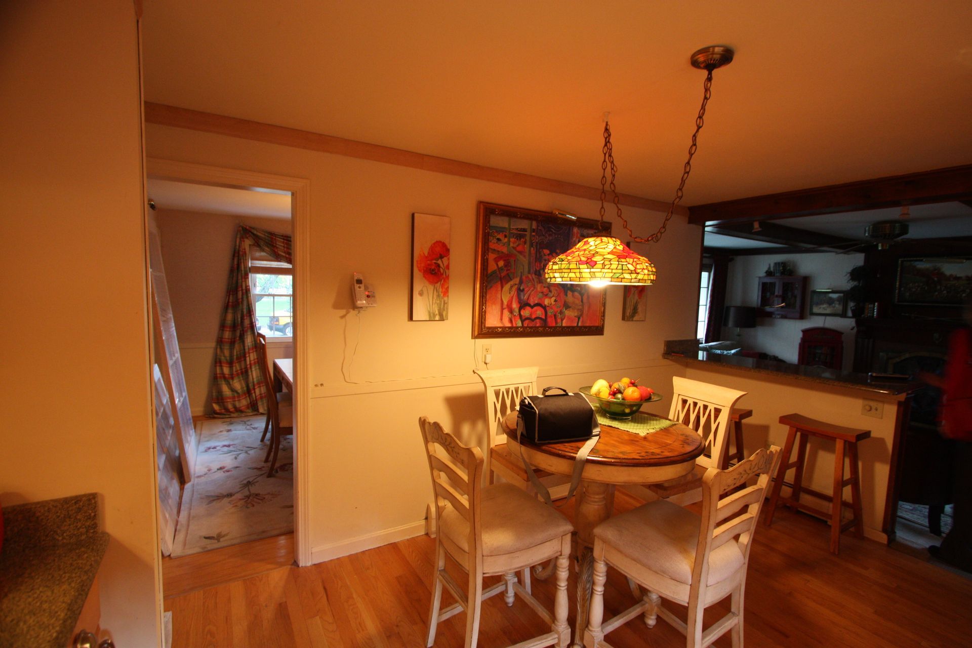 A dining room with a table and chairs and a lamp hanging from the ceiling.