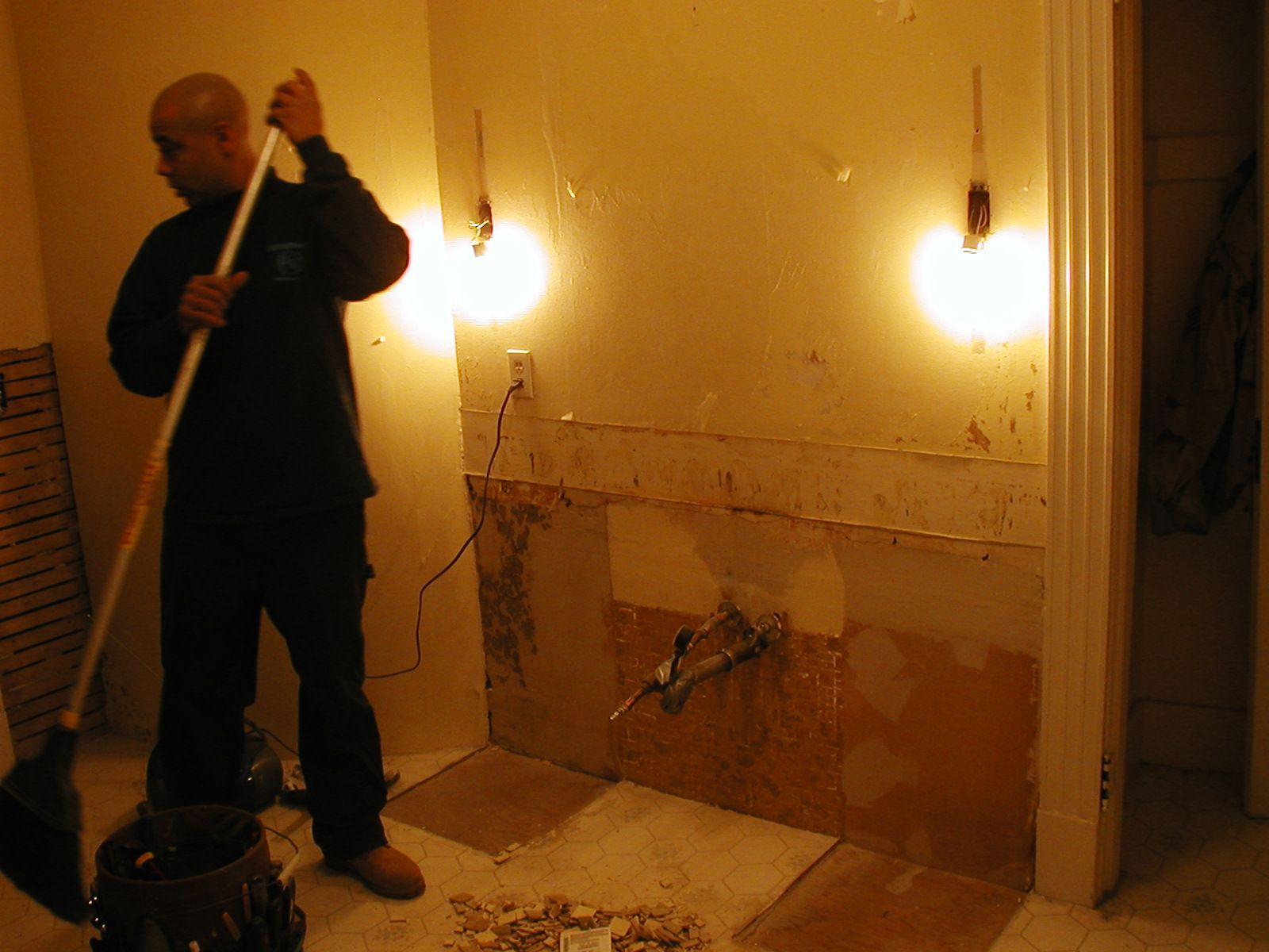A man is cleaning a bathroom with a broom.