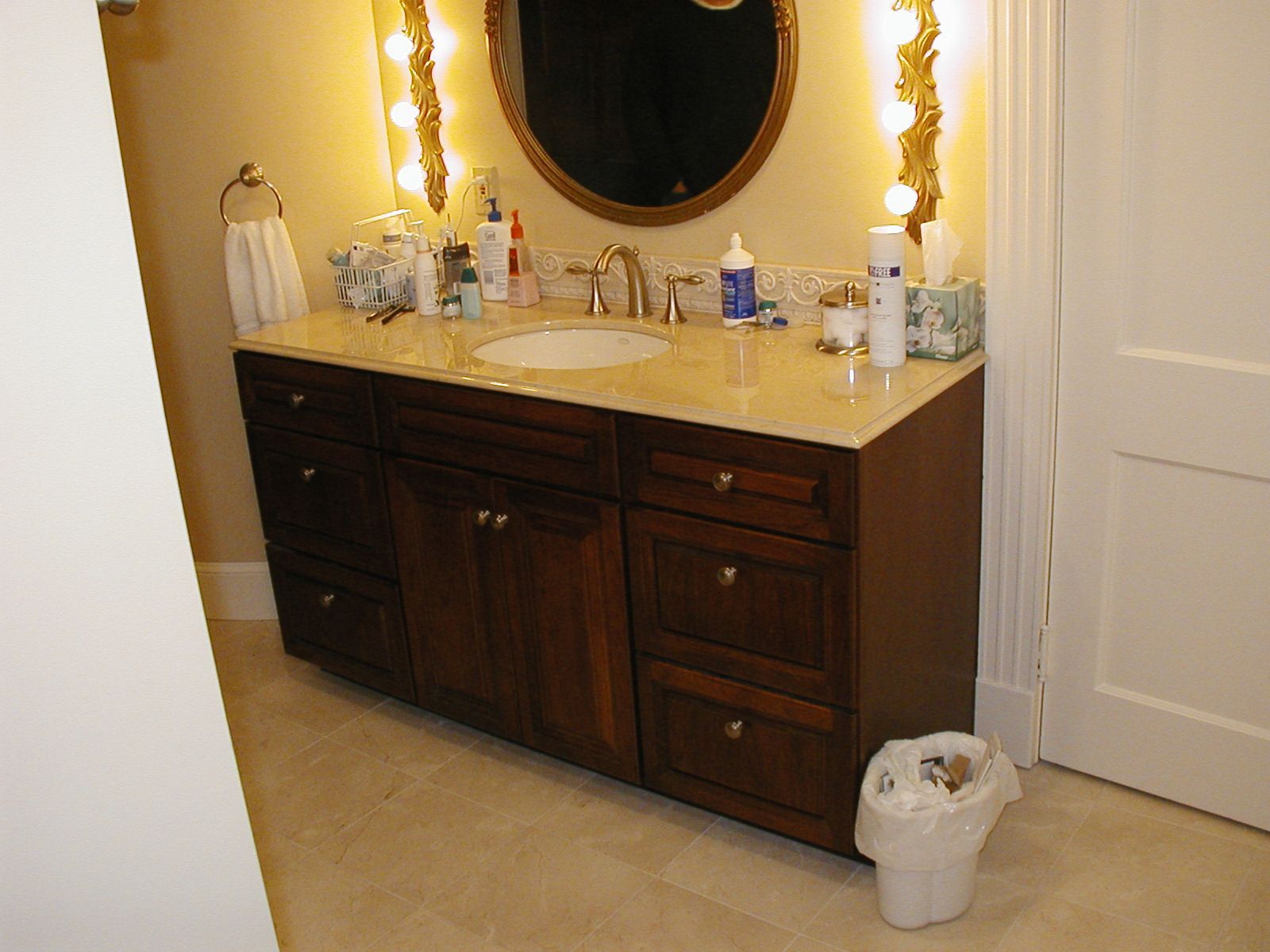 A bathroom with two sinks a mirror and a trash can.