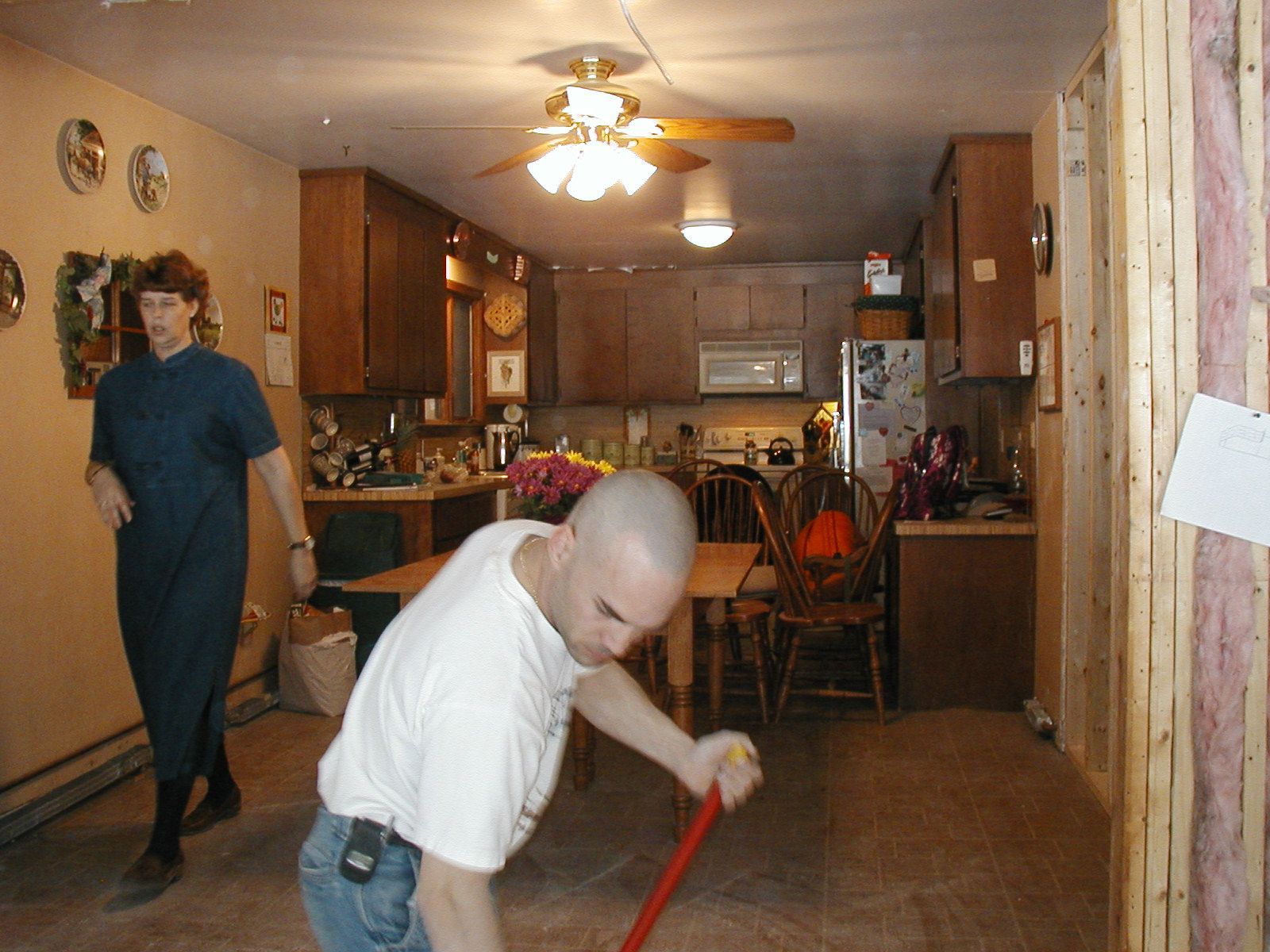 A man is sweeping the floor in a kitchen.