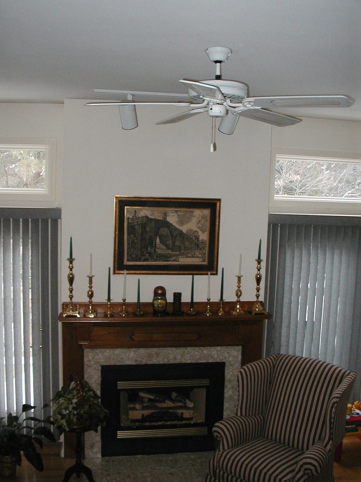 A living room with a fireplace and a ceiling fan.
