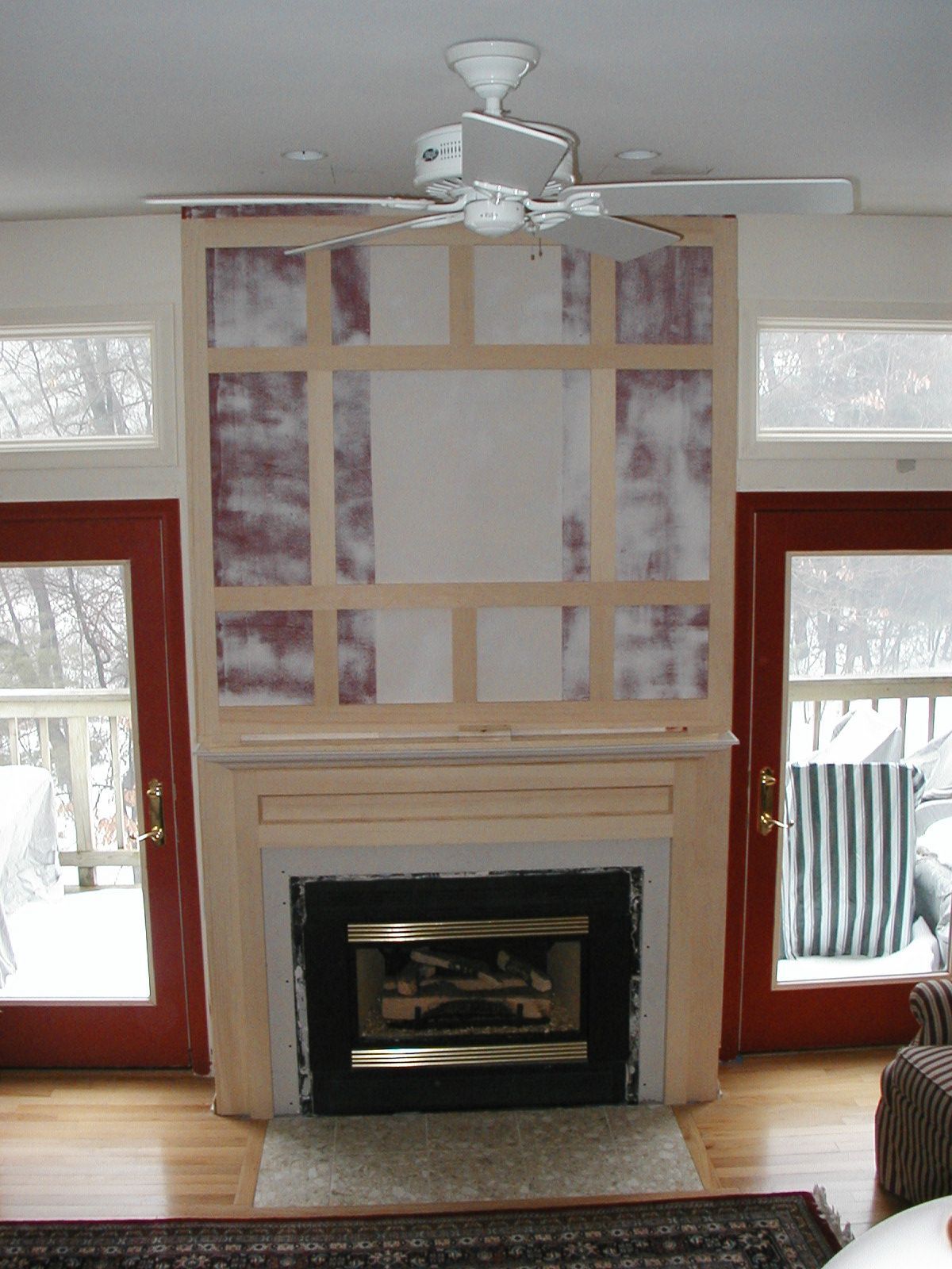 A living room with a fireplace and a ceiling fan.