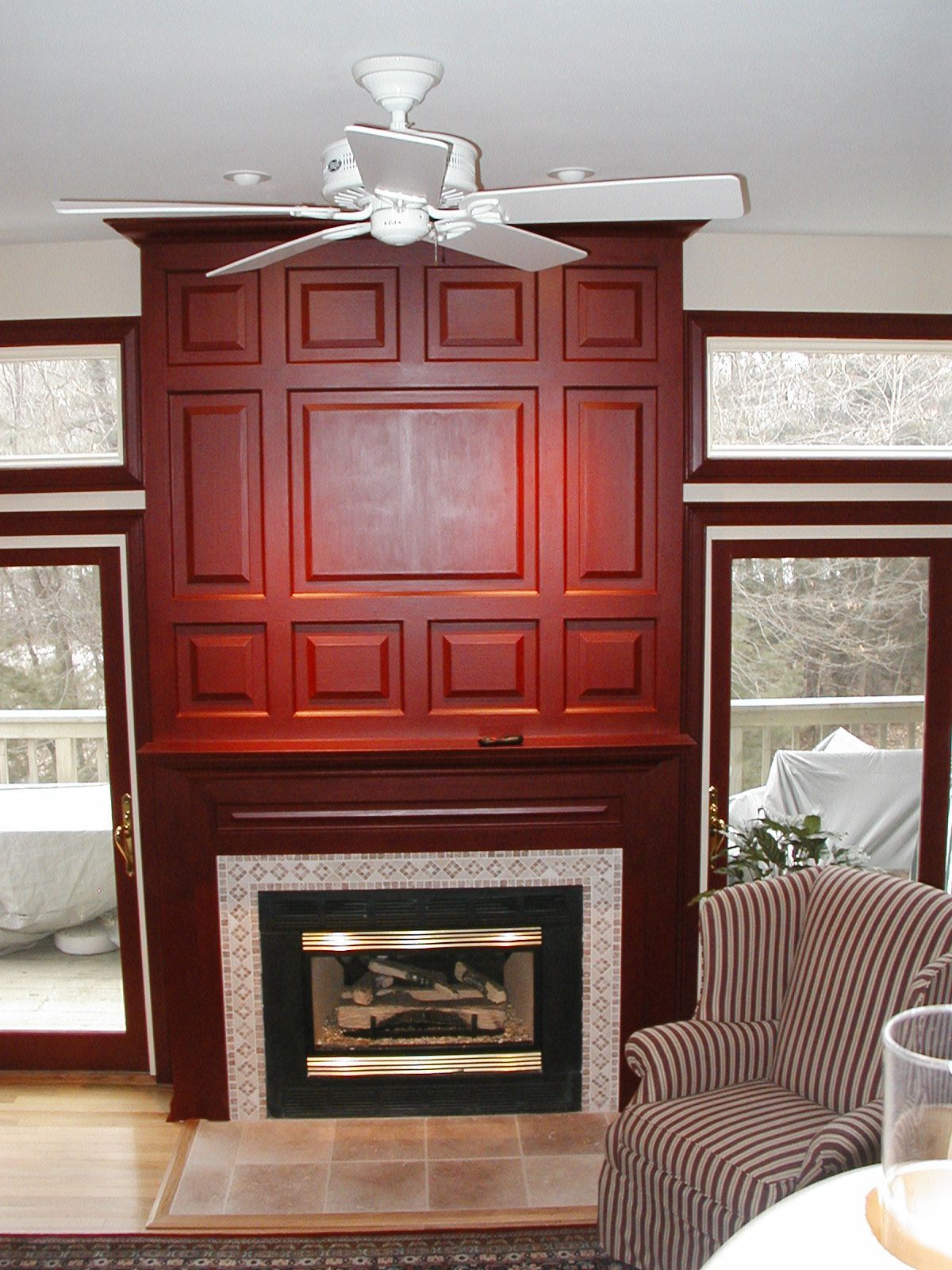 A living room with a fireplace and a ceiling fan.