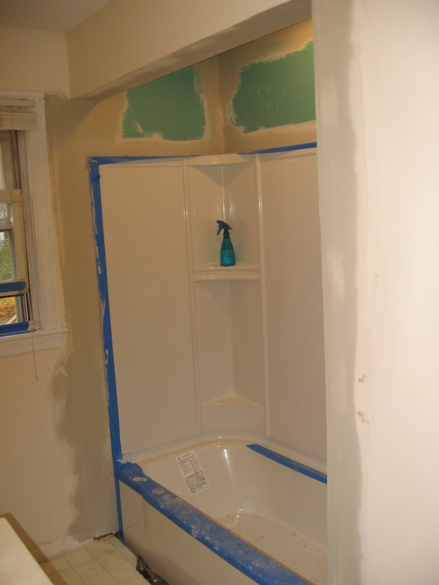 A bathroom with a bathtub and a spray bottle on the shelf.