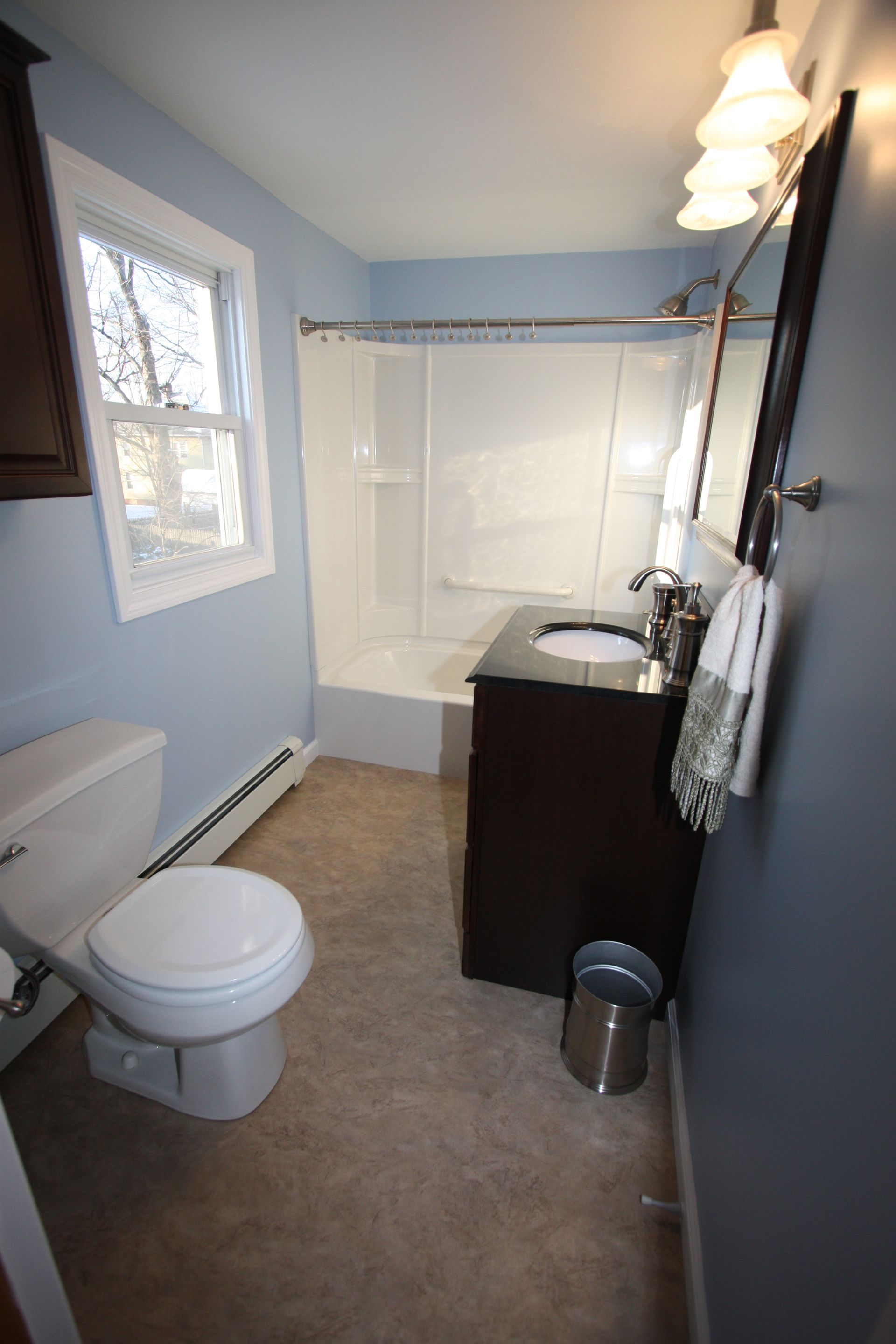 A bathroom with pink tiles, a sink, a toilet, and a window.