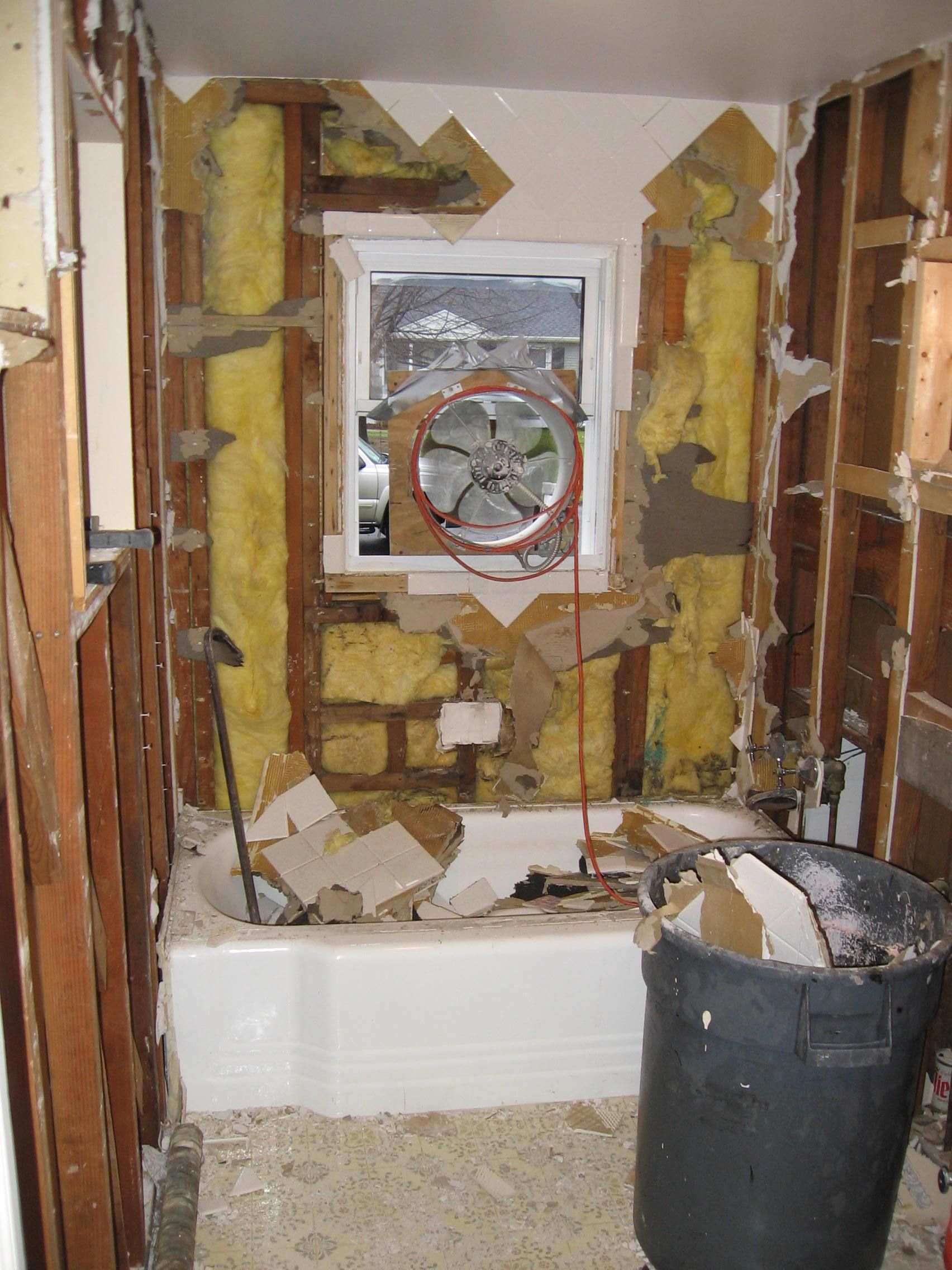 A bathroom under construction with a window and a fan.