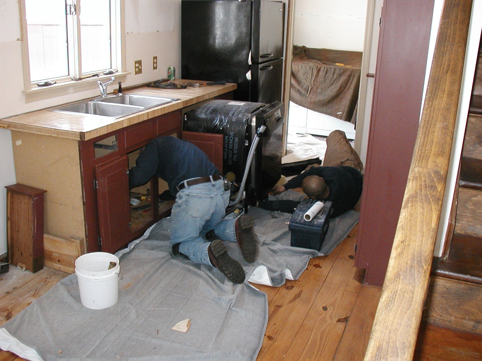 A man is working under a sink in a kitchen.