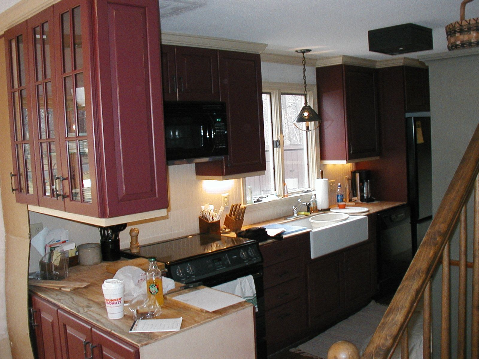 A kitchen with red cabinets and a white sink.