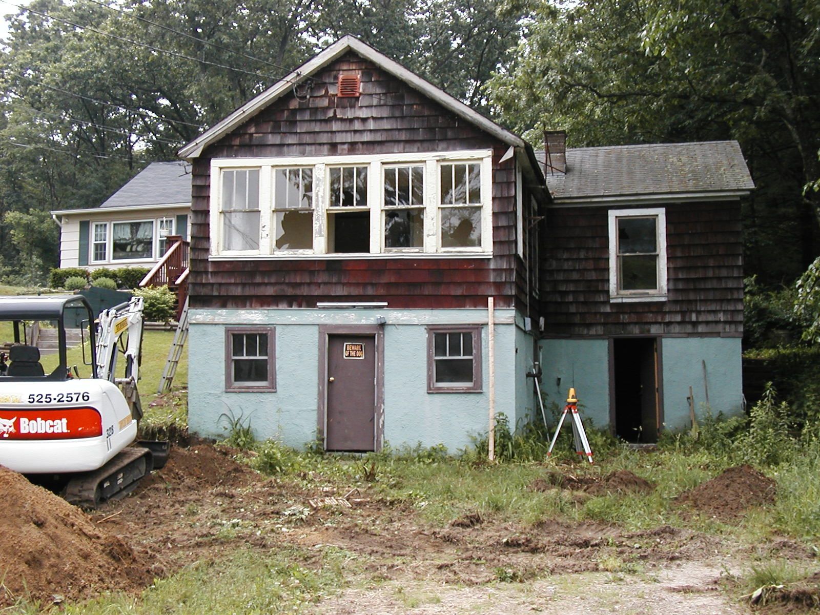 A bobcat excavator sits in front of a house.