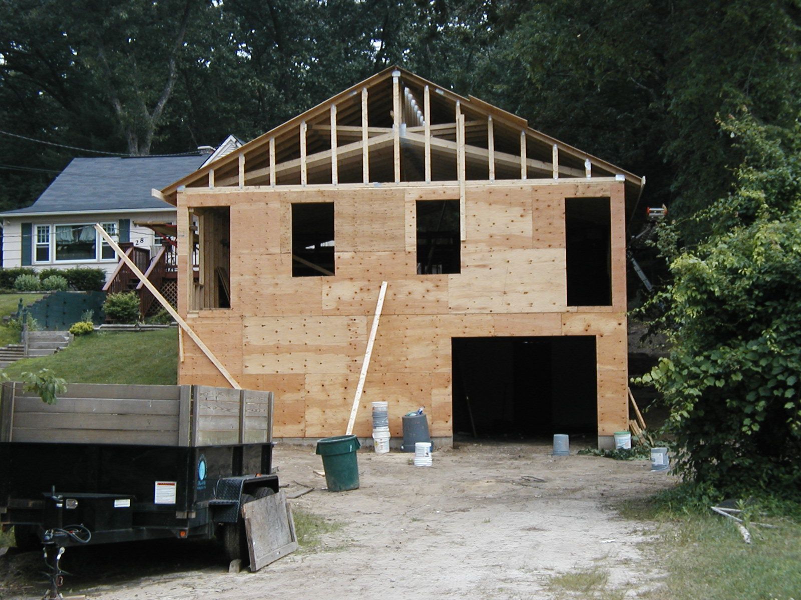 A house under construction with a trailer parked in front of it.