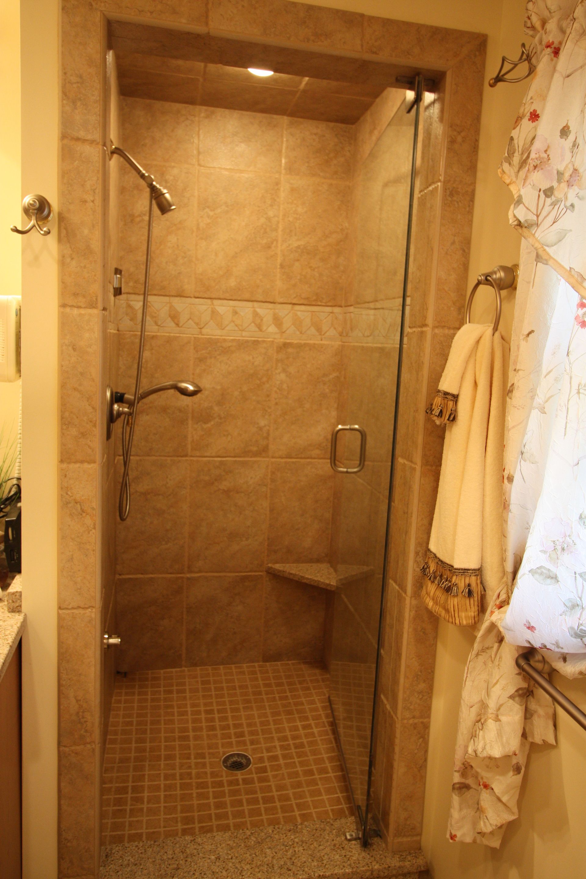 A bathroom with a walk in shower with a glass door.