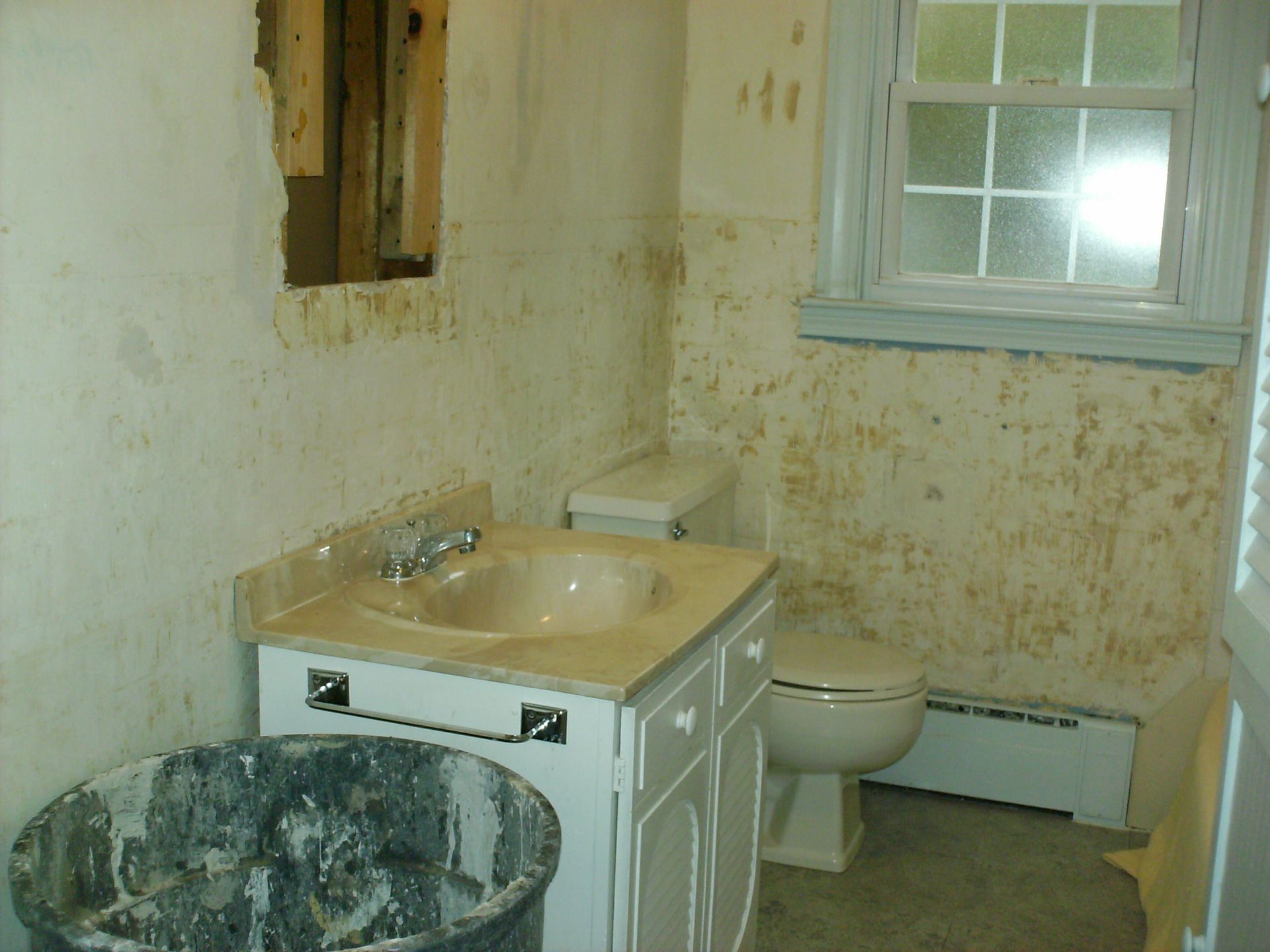 A bathroom with a sink, a toilet, and a window.
