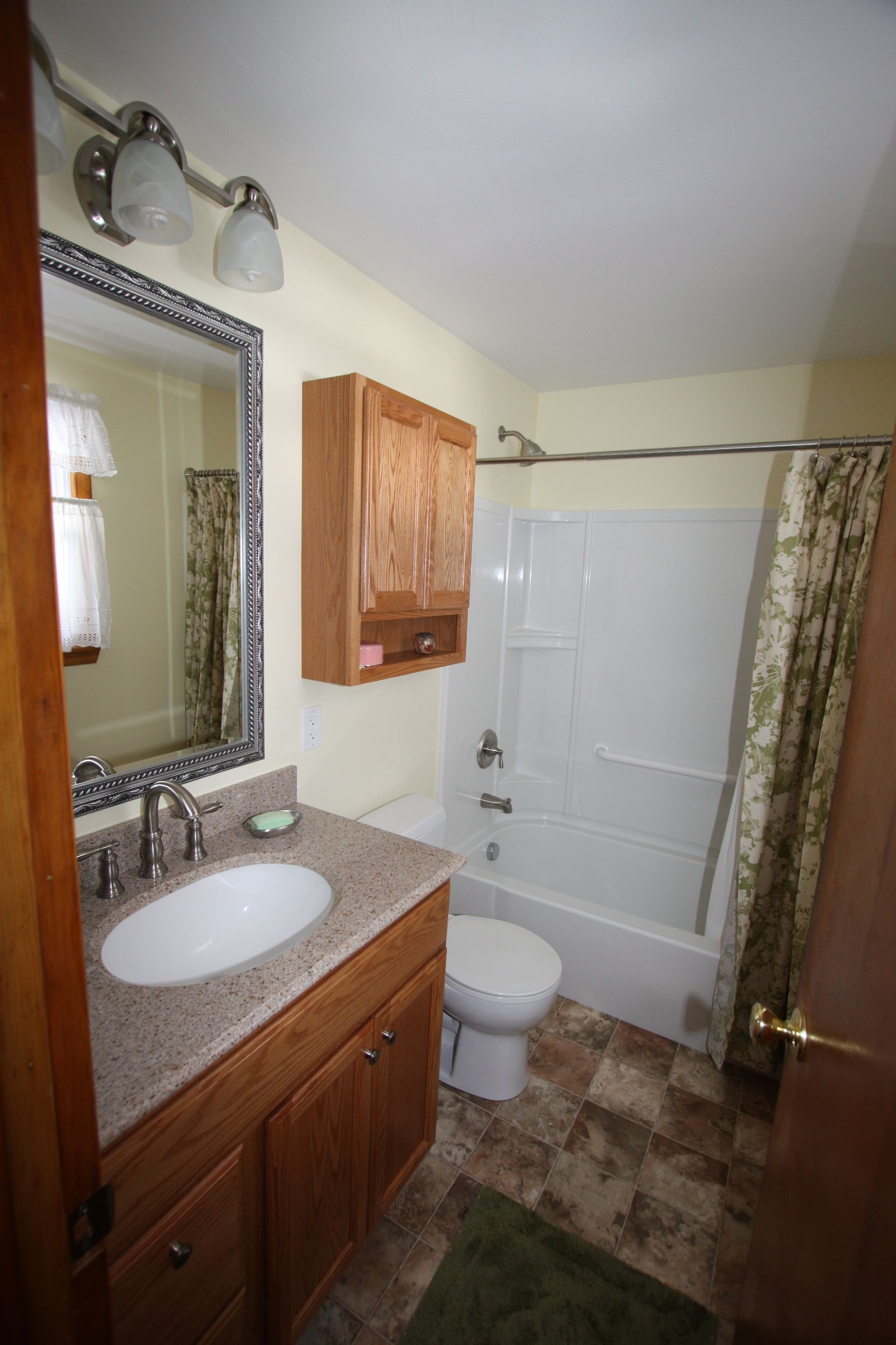 A bathroom with a sink, toilet, tub, and mirror.