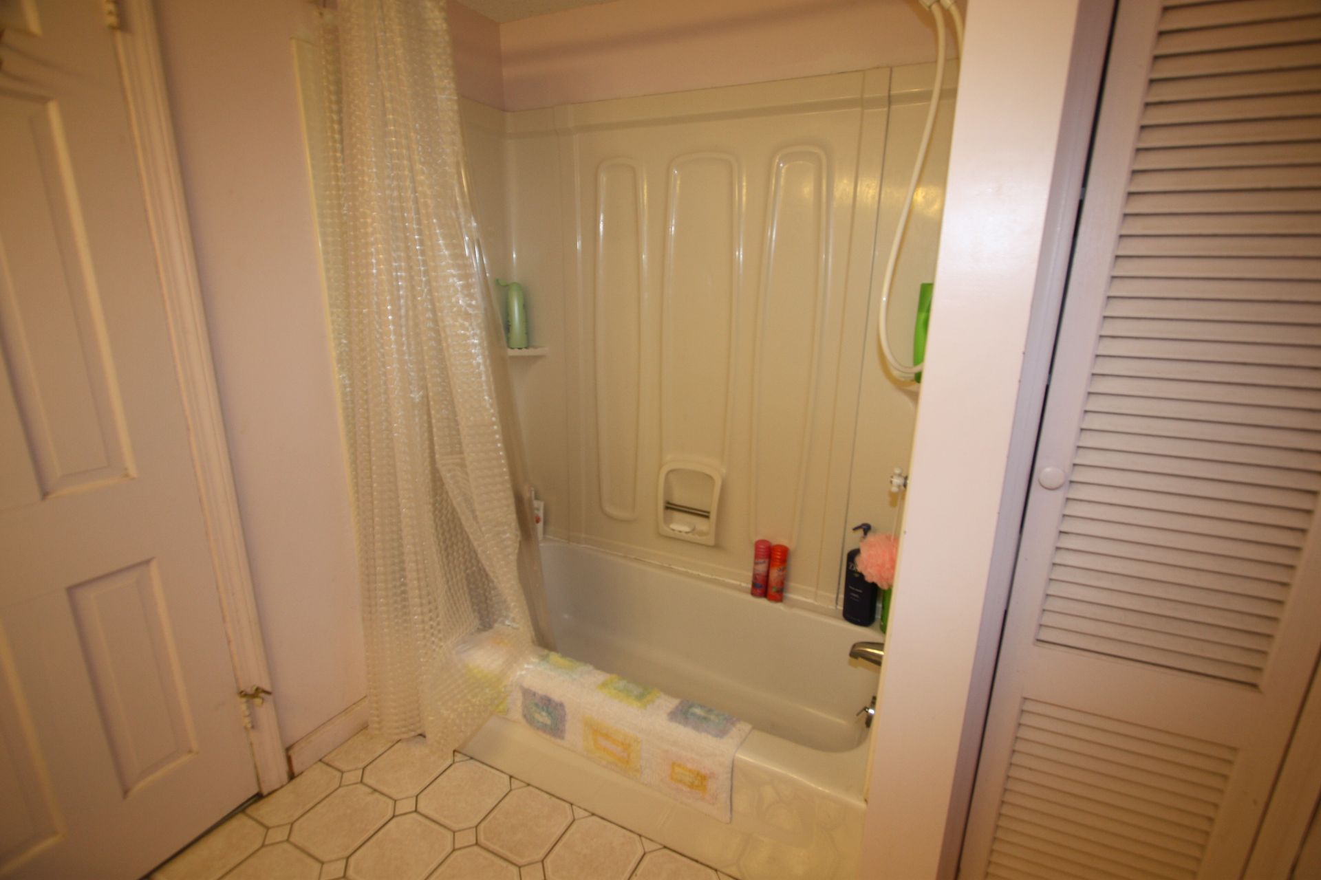 A bathroom with a tub, shower, and closet.