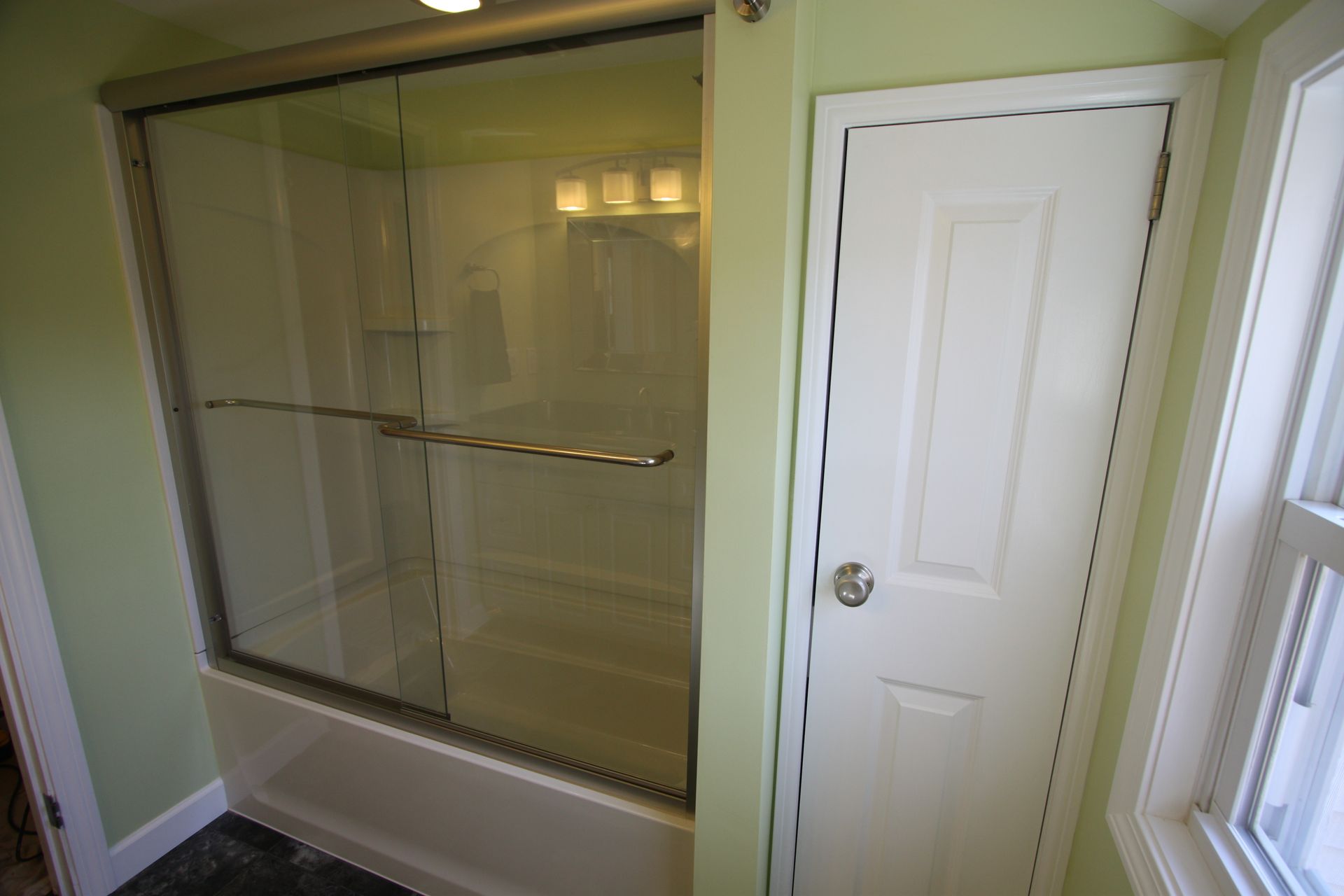 A bathroom with a sliding glass shower door and a window.