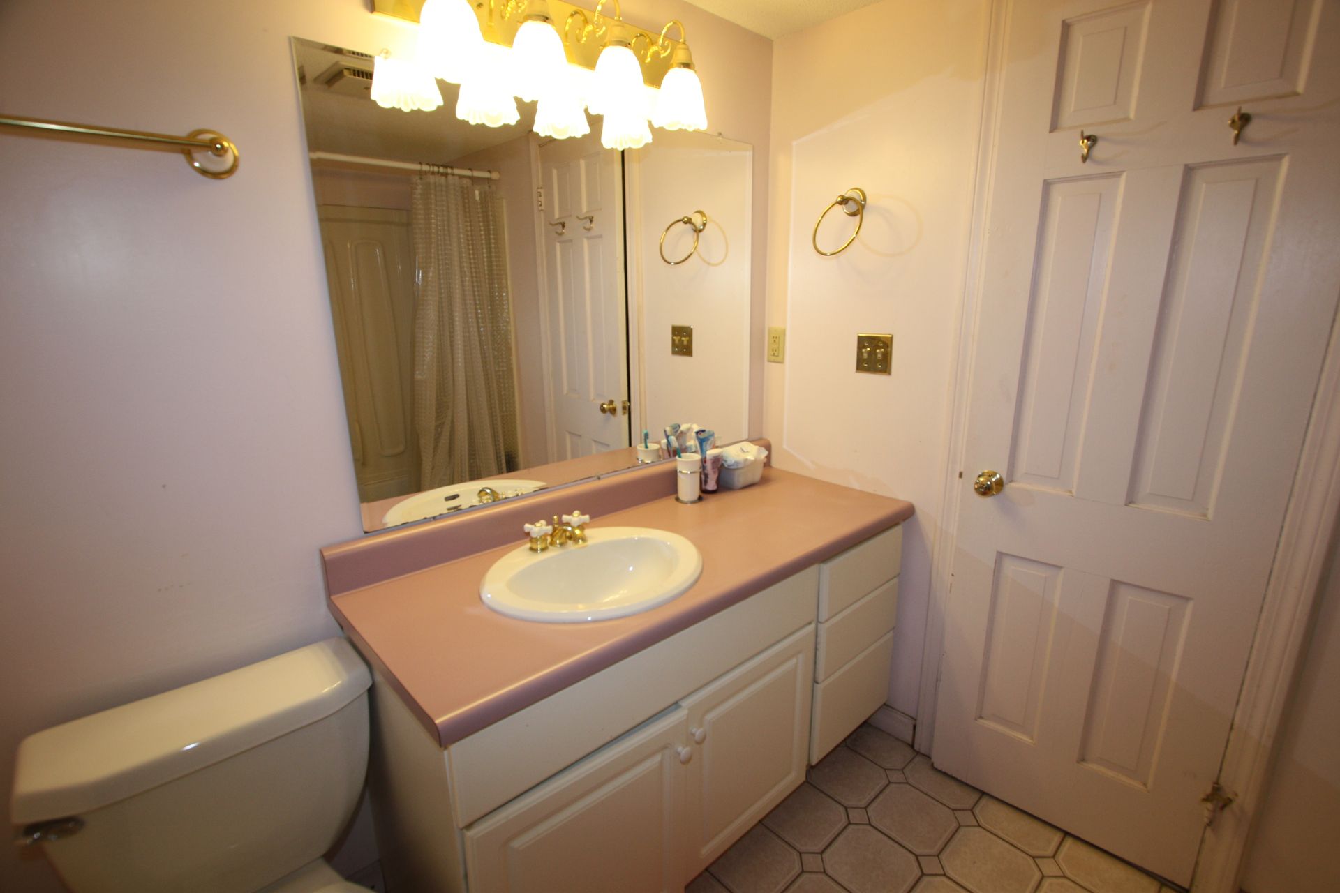 A bathroom with a toilet, sink, and mirror.