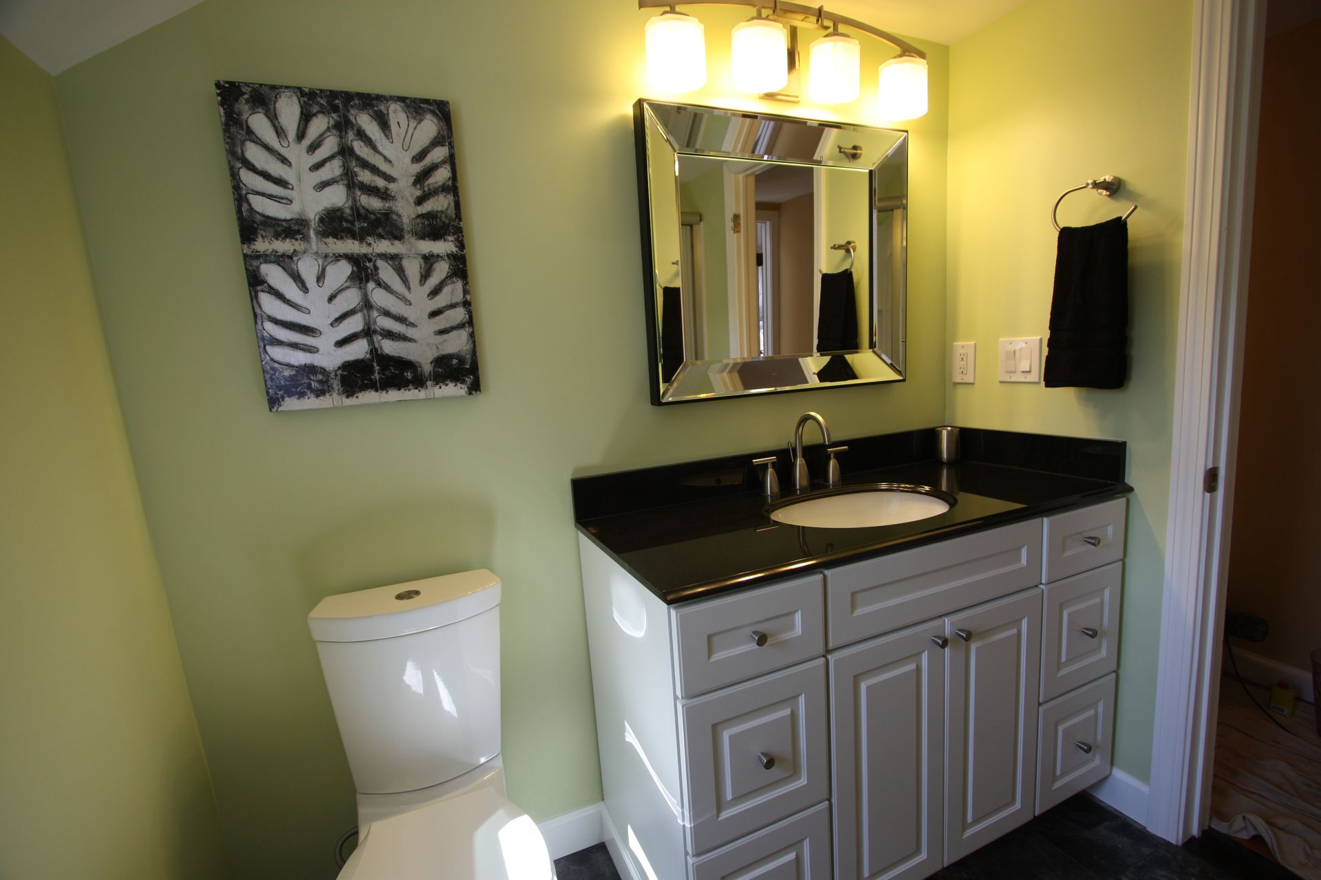 A bathroom with a toilet, sink, and mirror.