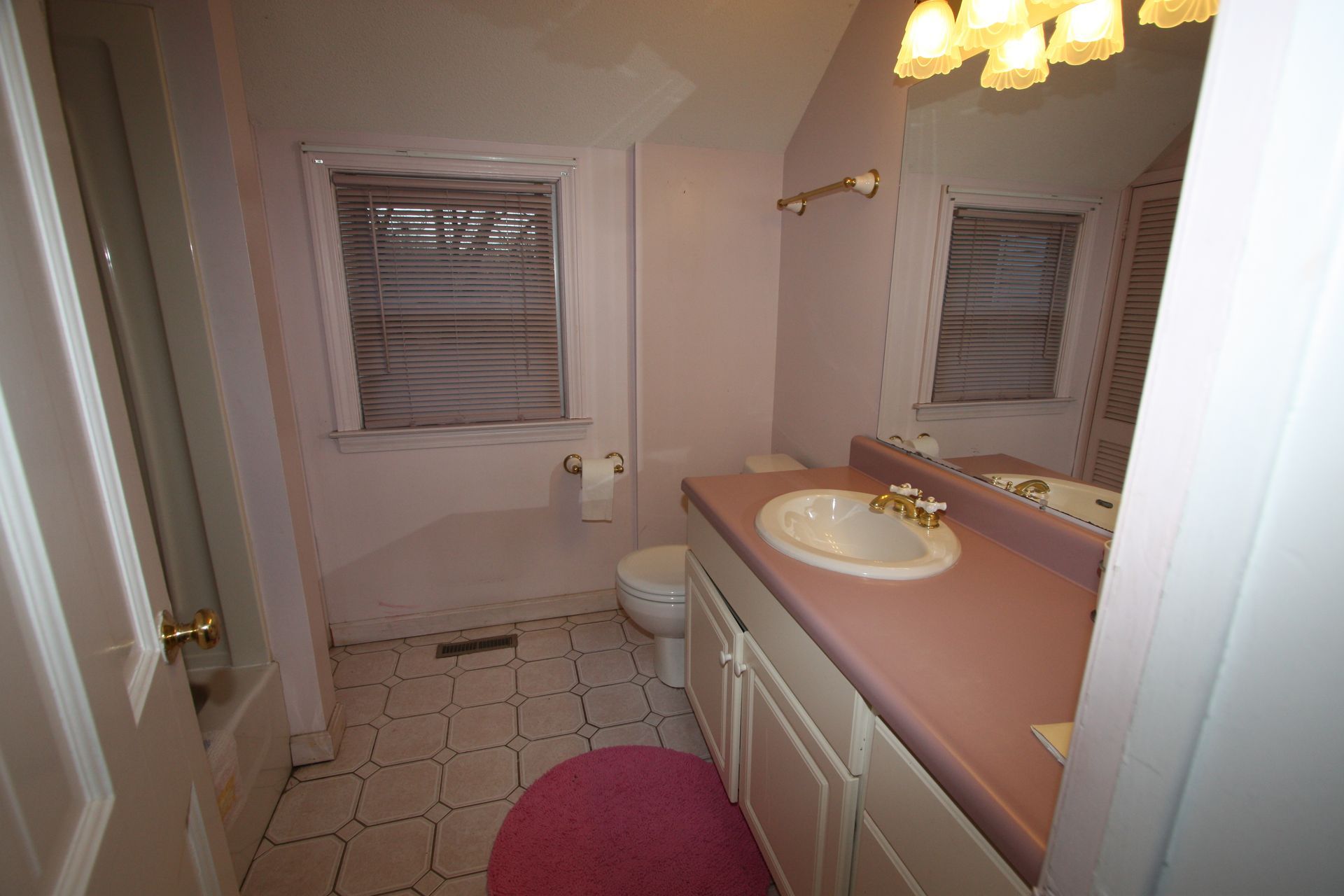 A bathroom with a sink, a toilet, and a window.