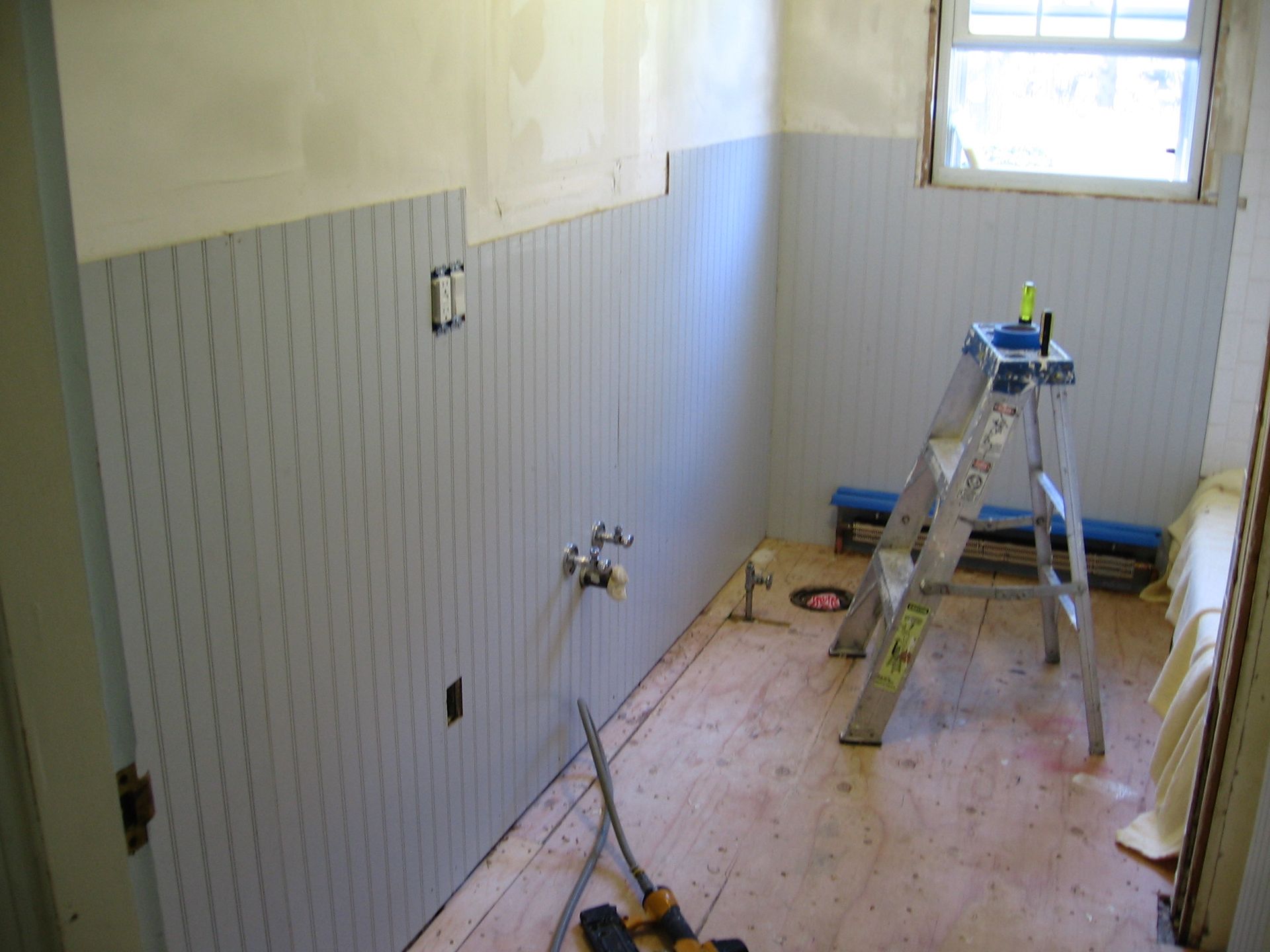 A ladder is sitting on the floor of a bathroom under construction.
