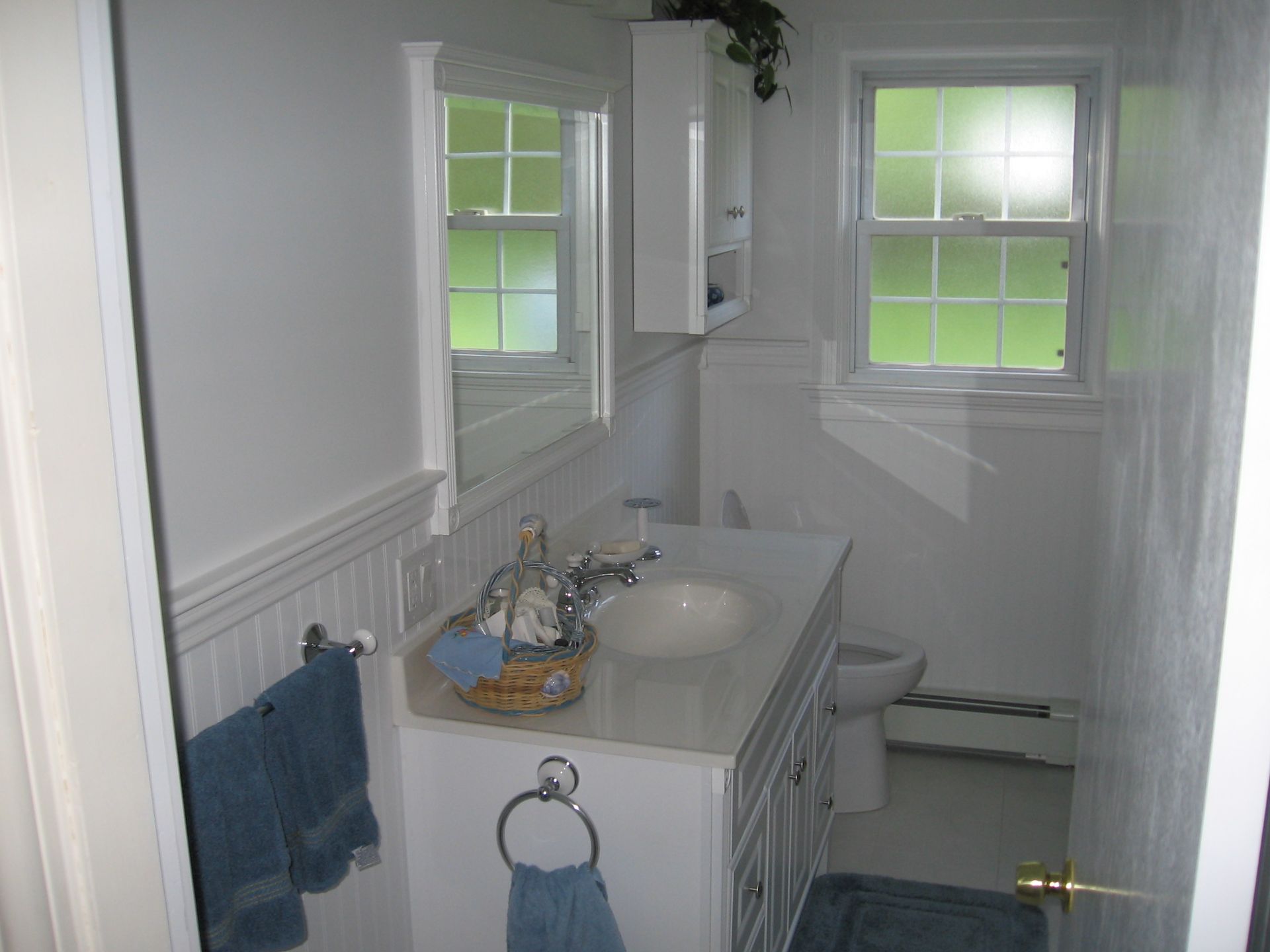 A bathroom with a sink a toilet and a window.