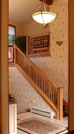 A wooden staircase with a chandelier hanging from the ceiling.