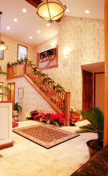 A hallway with a staircase and flowers on the floor.