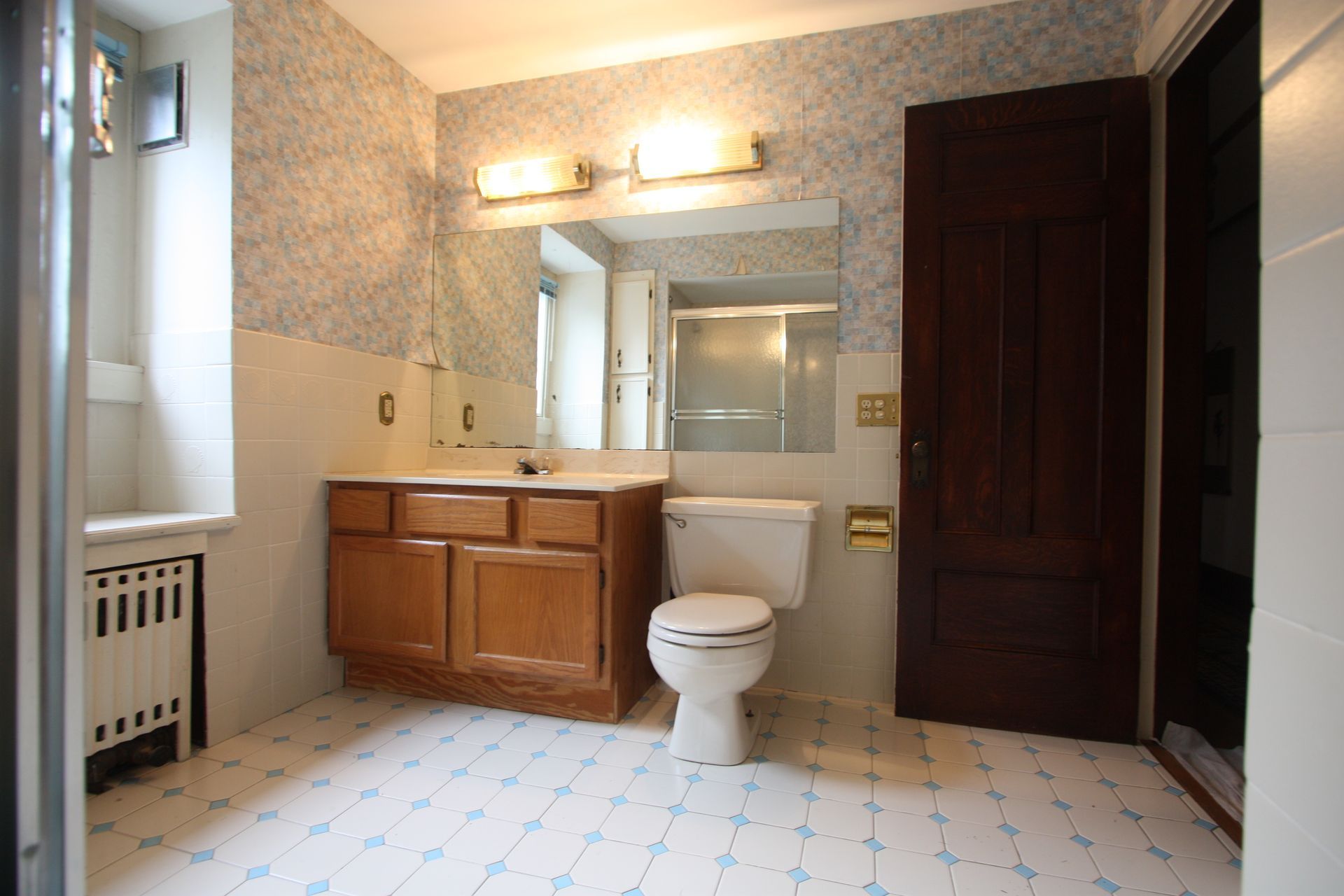 A bathroom with a toilet, sink, and mirror.
