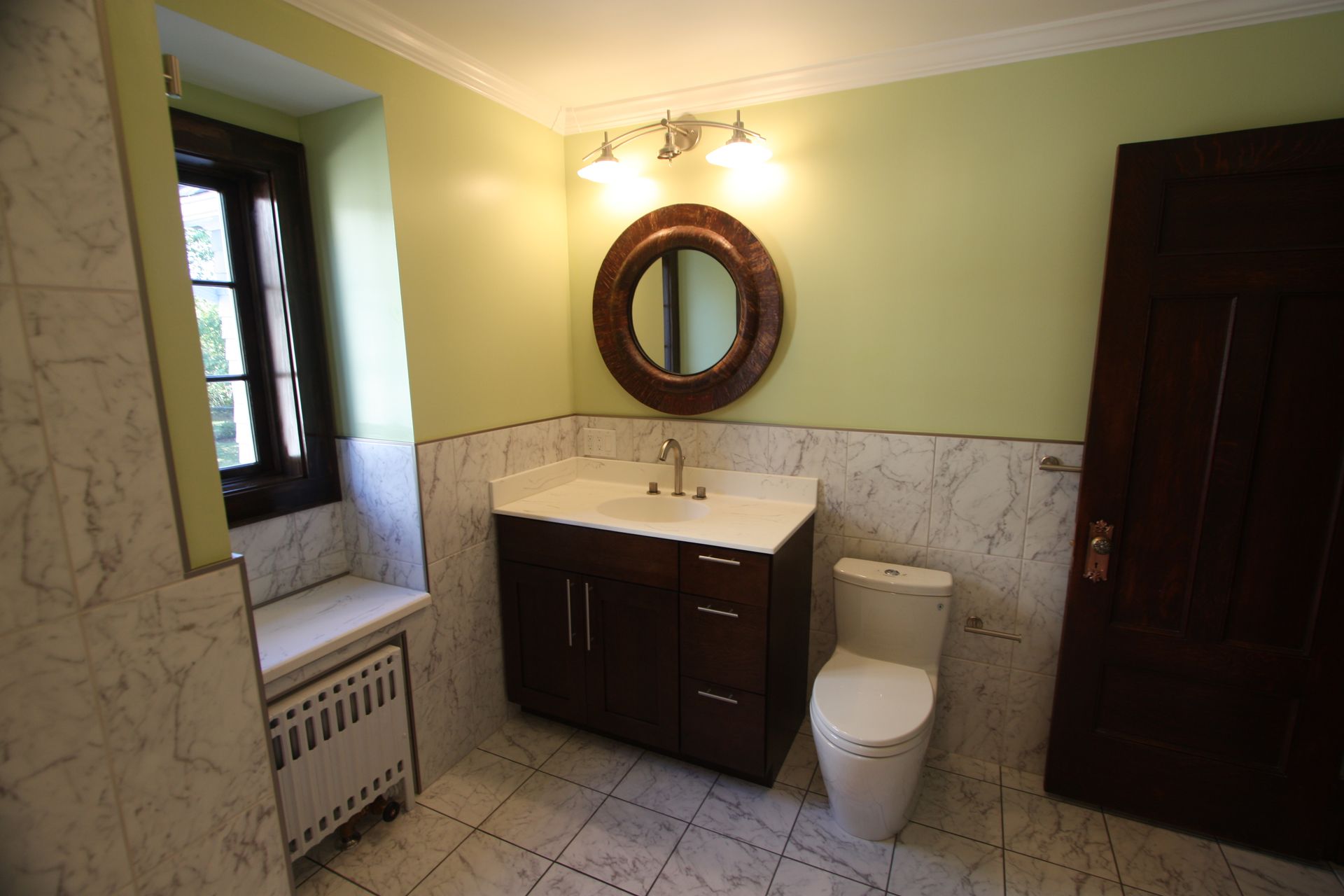 A bathroom with a toilet, a sink, and a mirror.
