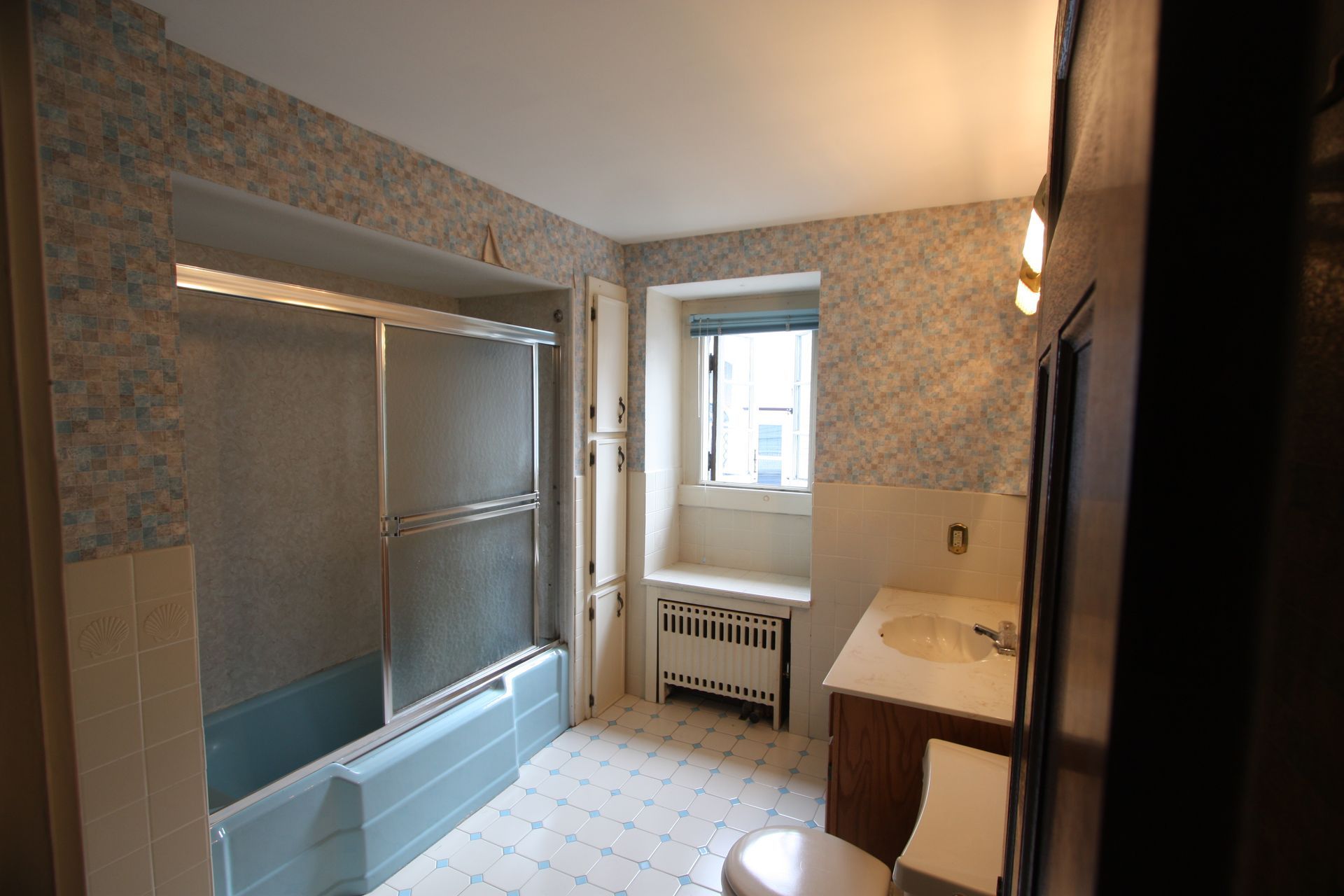 A bathroom with a tub, toilet, sink, and window.