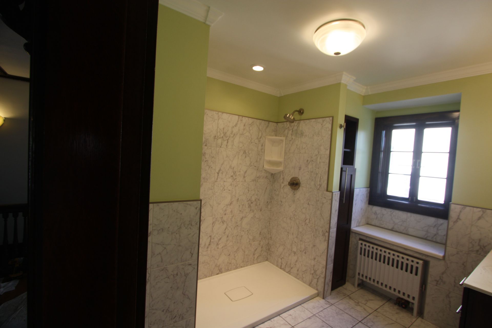 A bathroom with a walk in shower and a window.