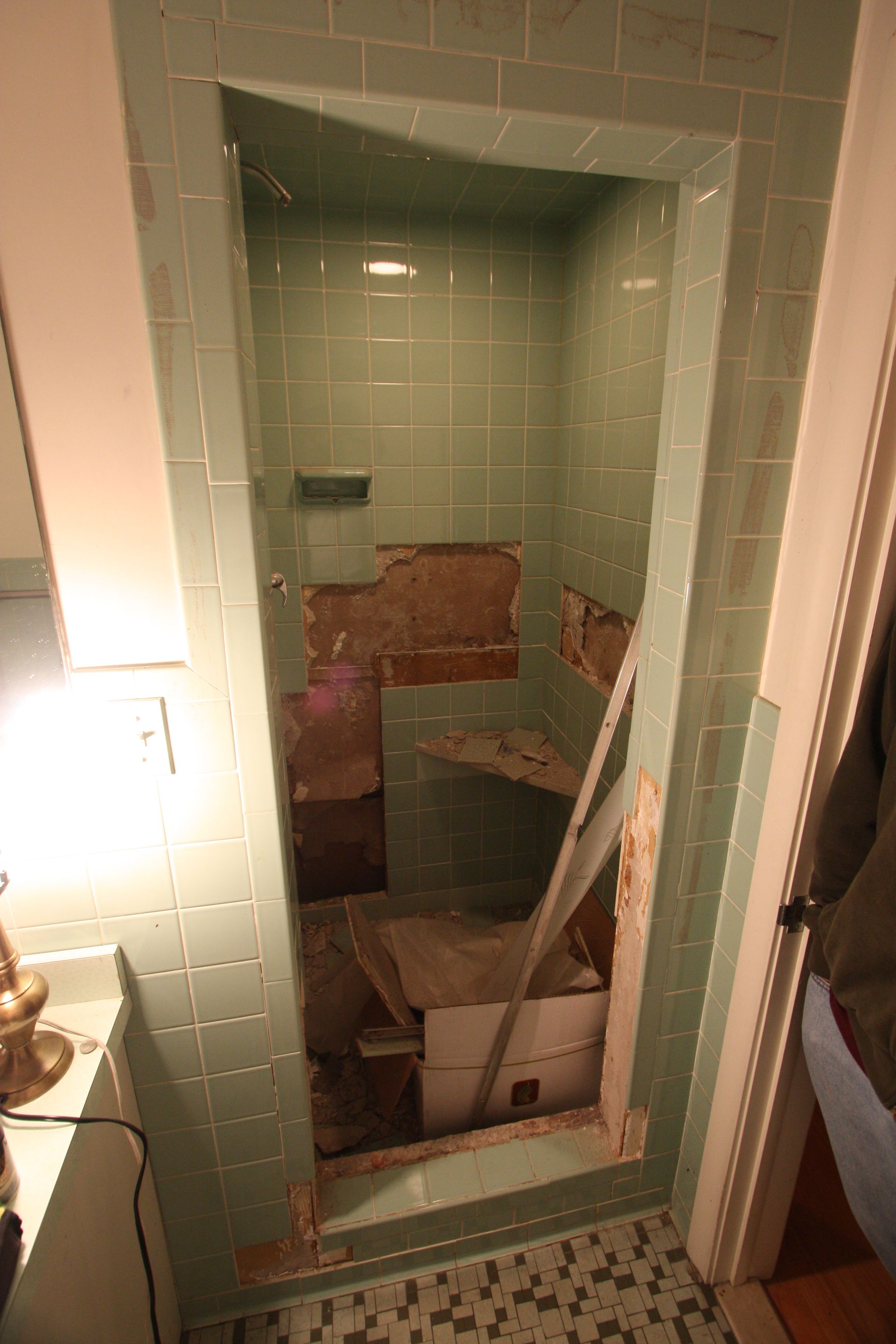 A bathroom with green tiles and a door that is open.